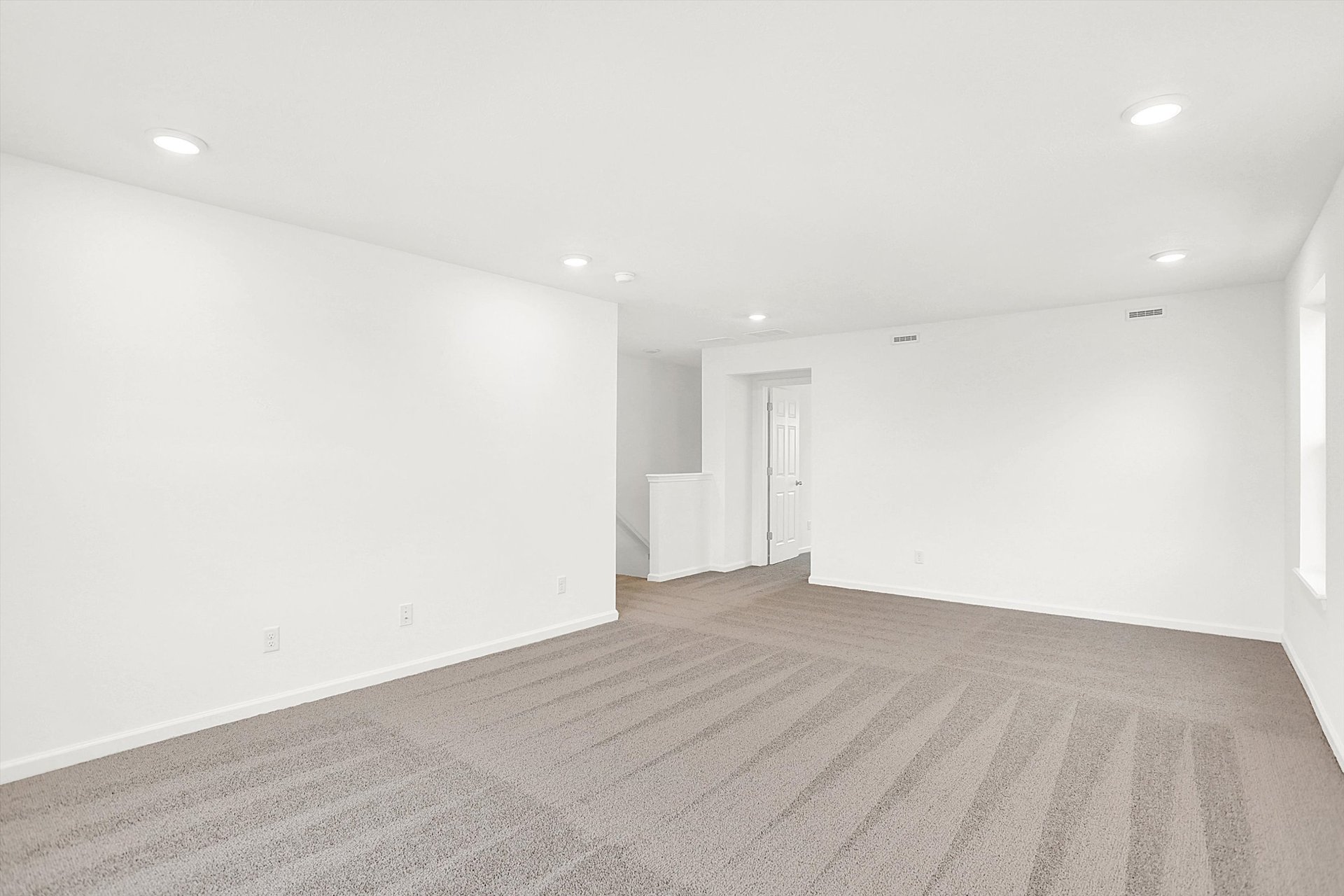 bonus room with tan carpet and white walls