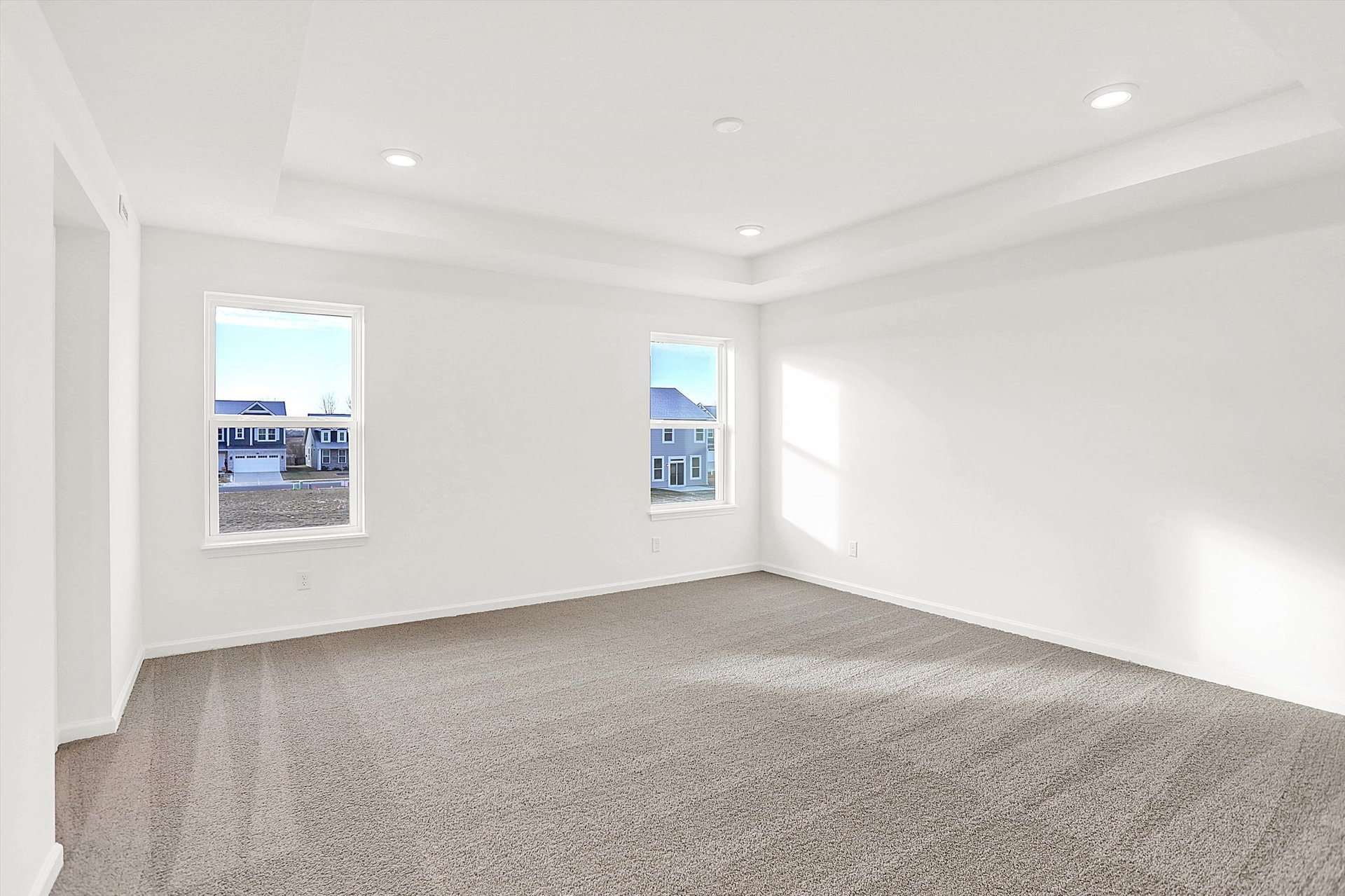 bedroom with tray ceiling and tan carpets