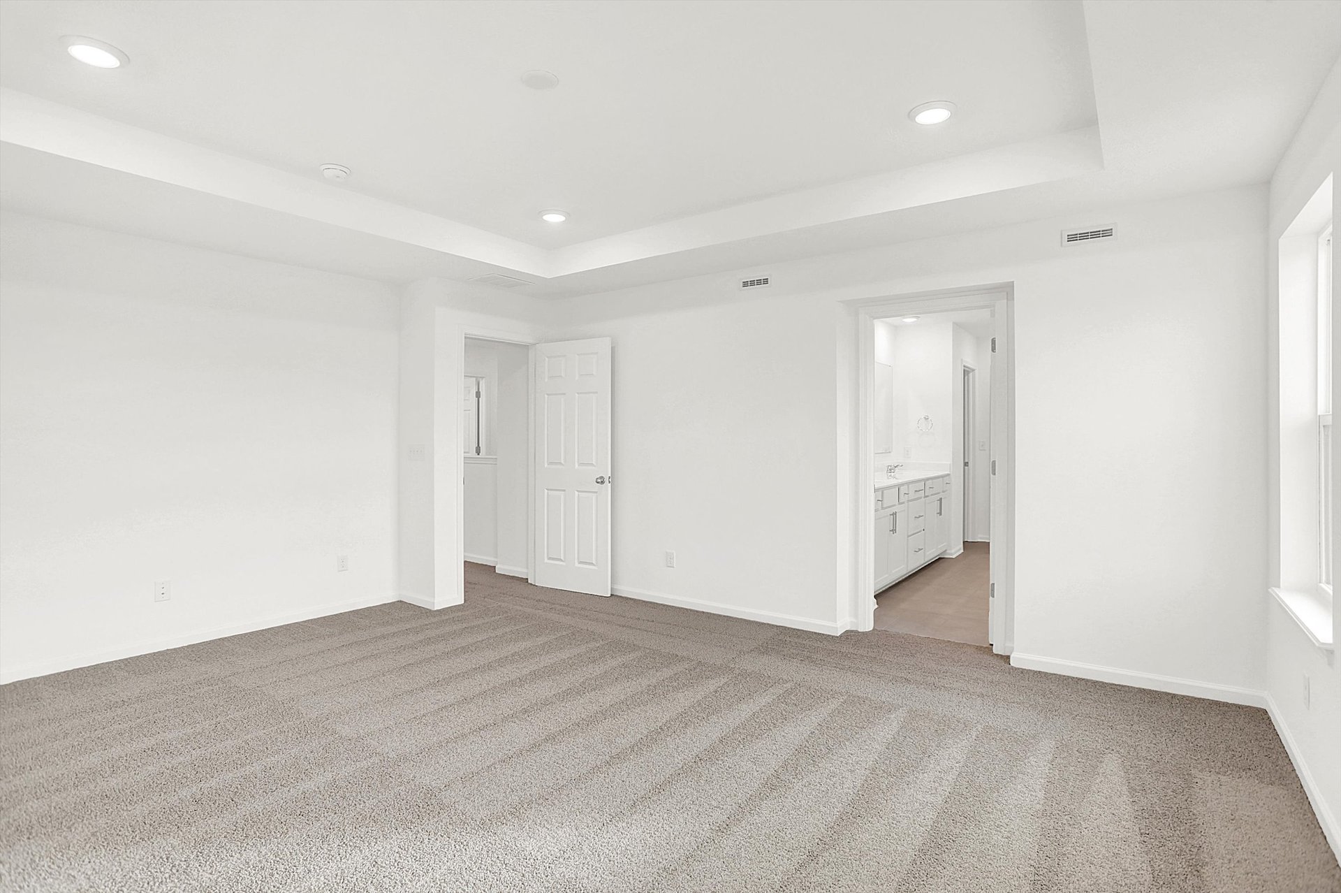 bedroom with tray ceiling and tan carpets