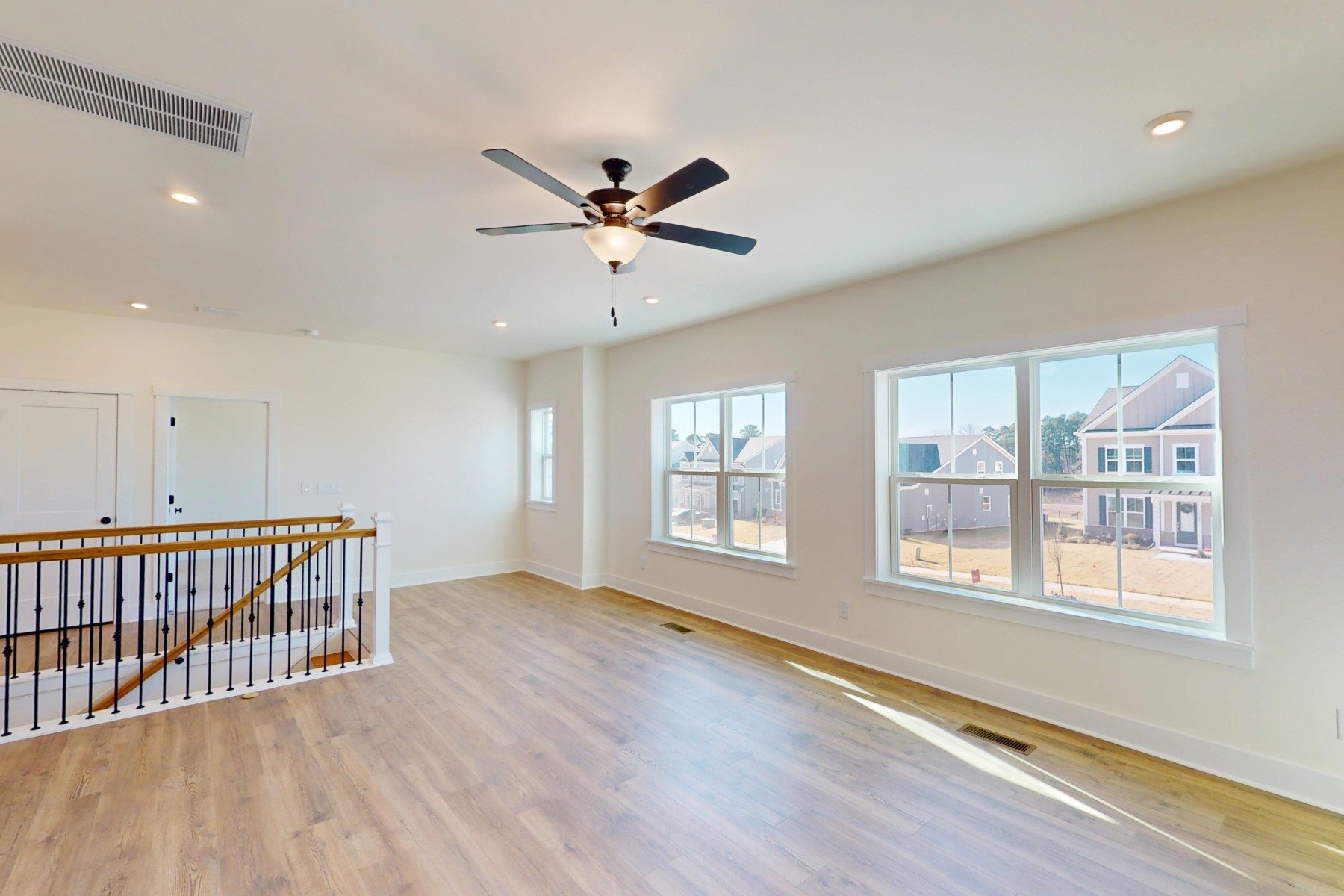 loft with a ceiling fan and windows