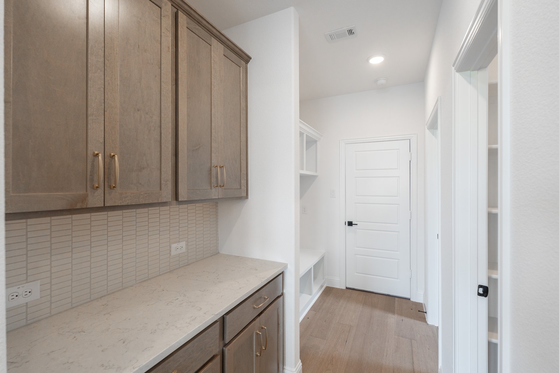 mudroom with wood floors and brown cabinets 
