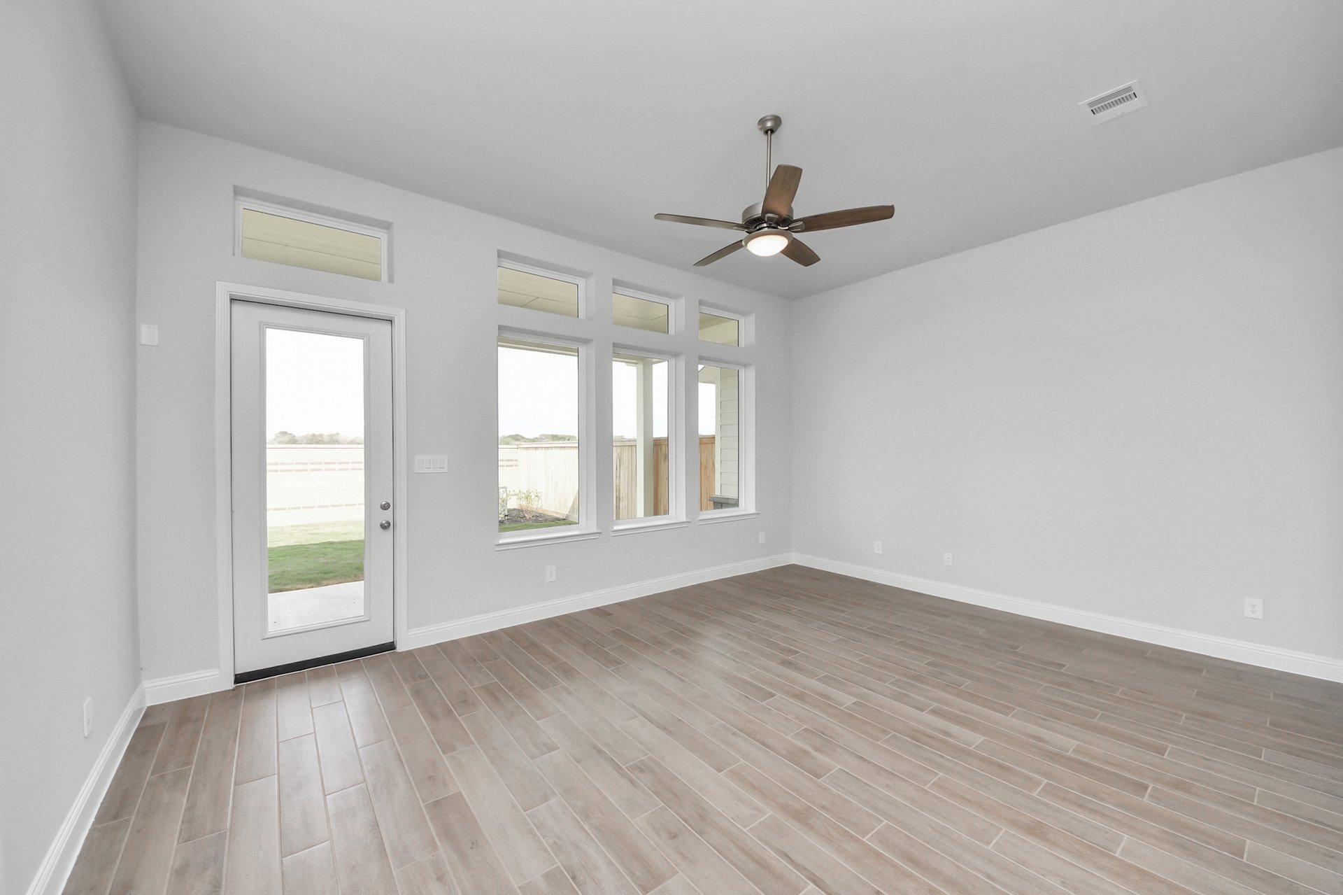 open-concept room with large windows and ceiling fan