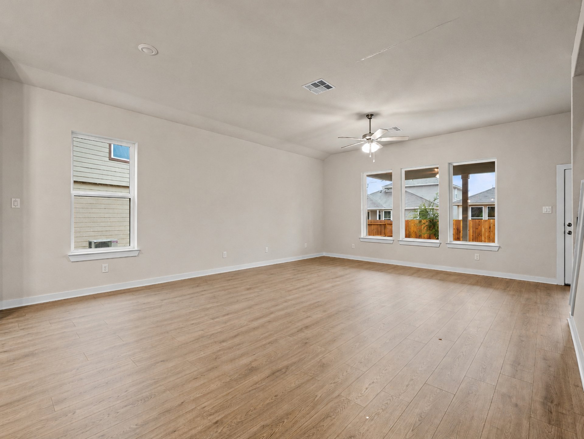 great room with brown flooring, windows, ceiling fan