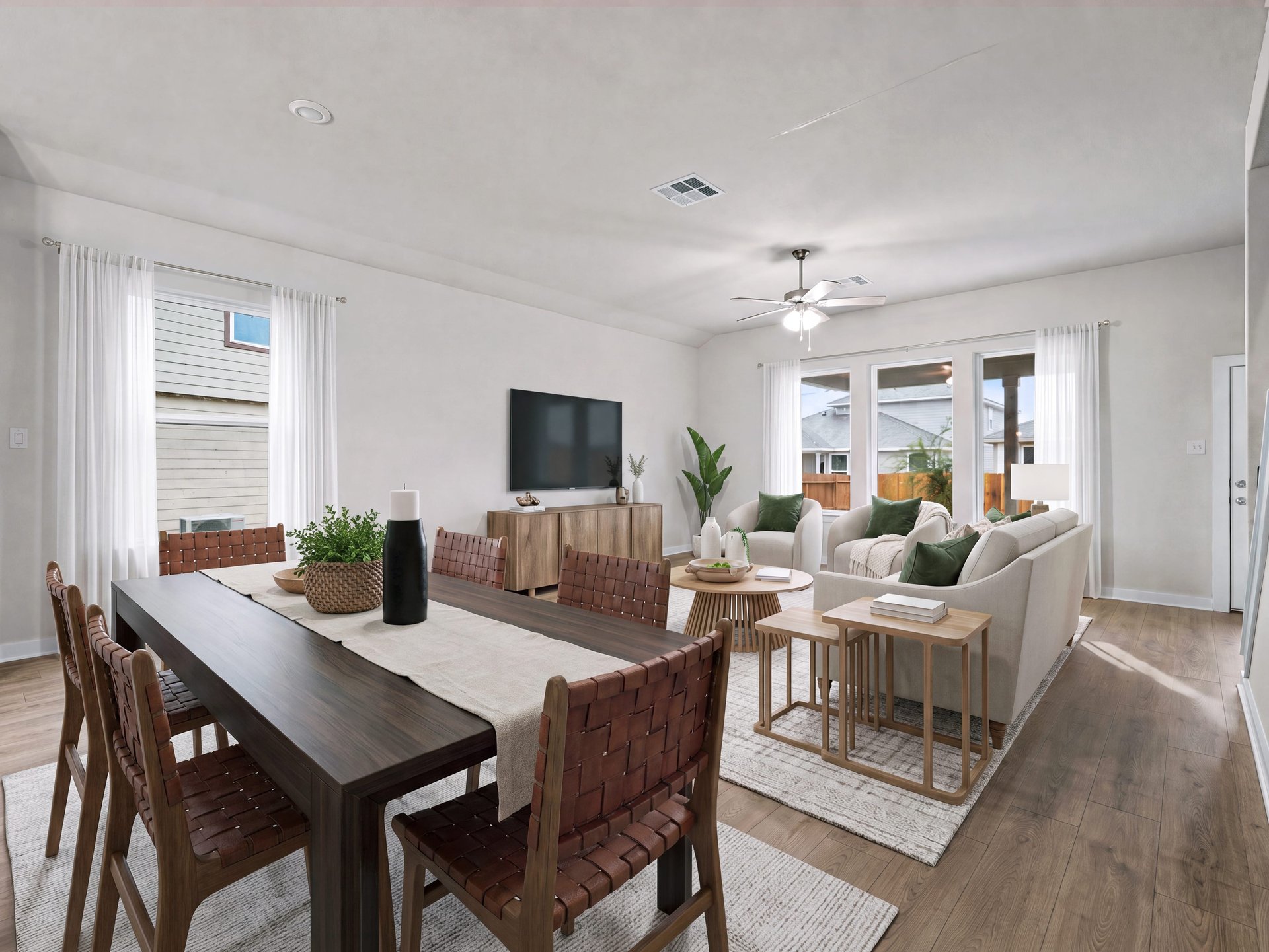 great room with brown flooring, windows and a ceiling fan