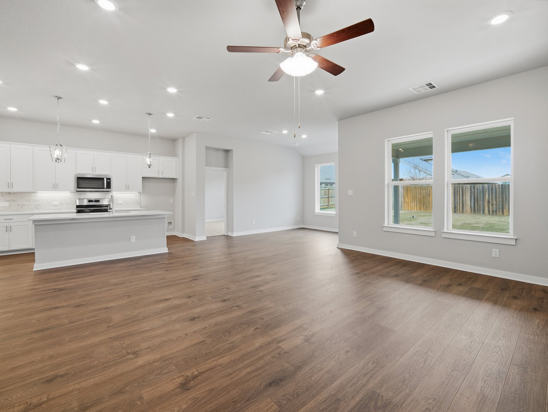 great room and dining with brown floors, windows, ceiling fan 