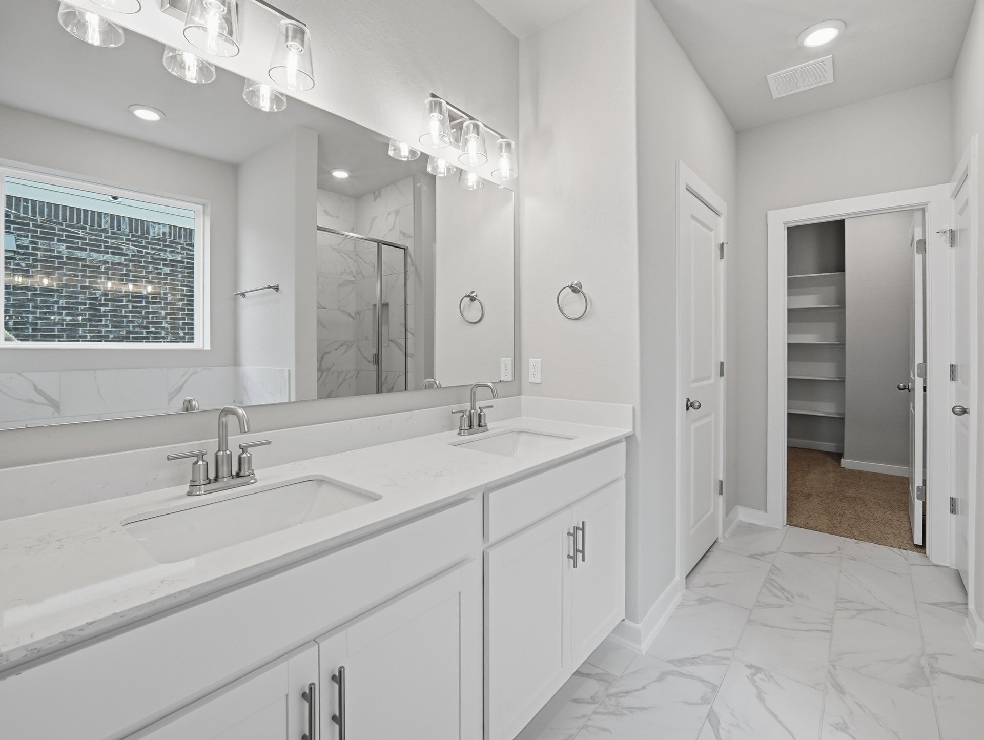 bathroom with dual sinks, mirror and pendant lighting 