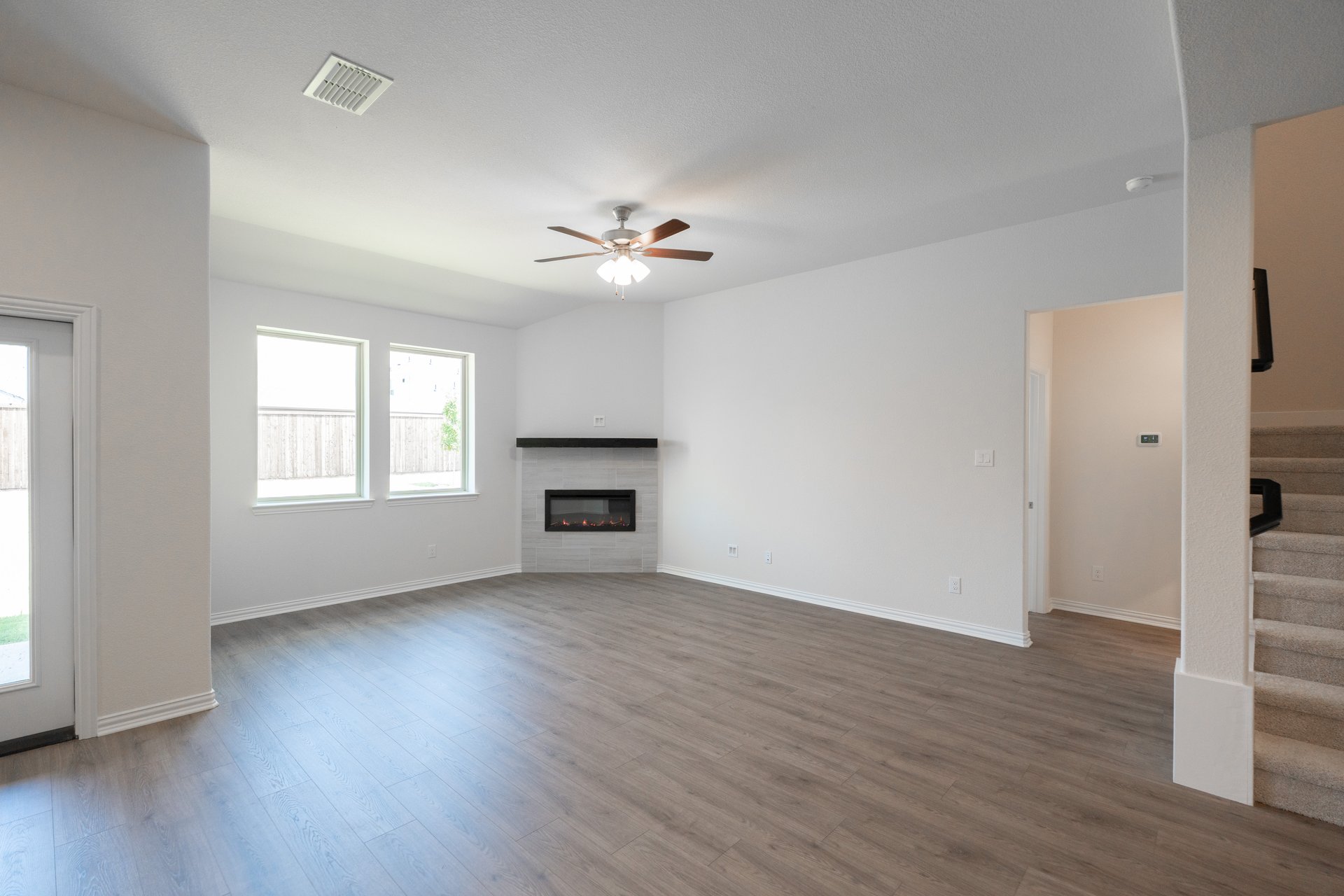 great room with fireplace and ceiling fan