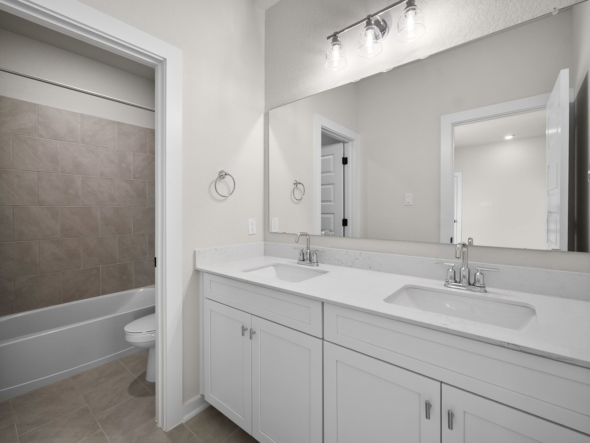 bathroom with dual sinks, quartz countertops & a bathtub