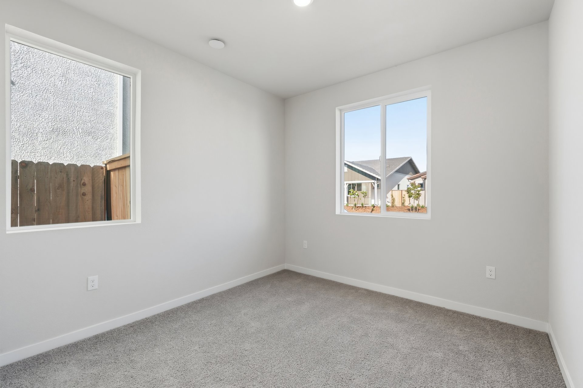 bedroom with gray carpet, white walls, two windows, and recessed ceiling light