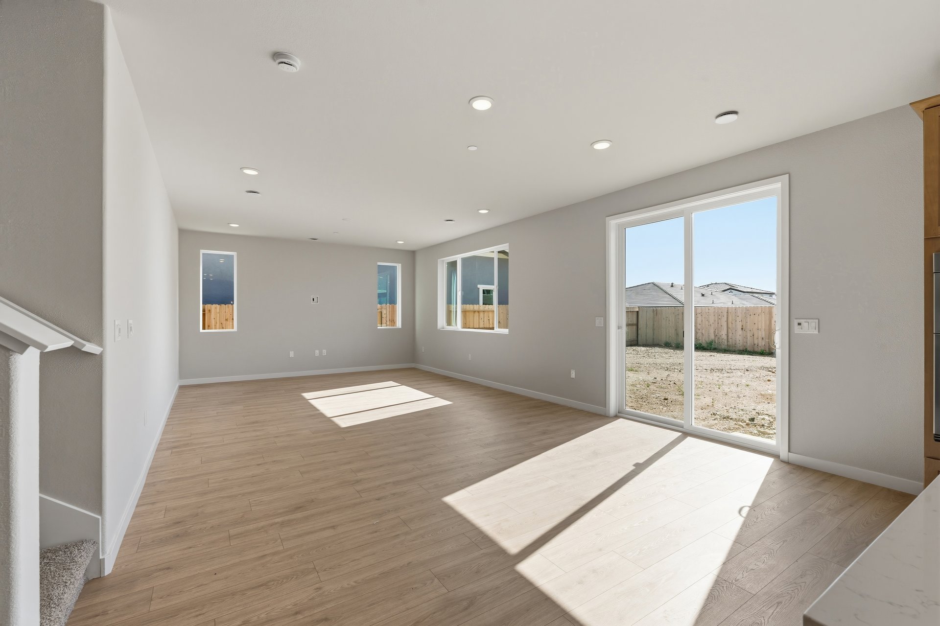 great room with light wood floors, multiple windows, sliding glass door that leads to backyard, and recessed ceiling lights