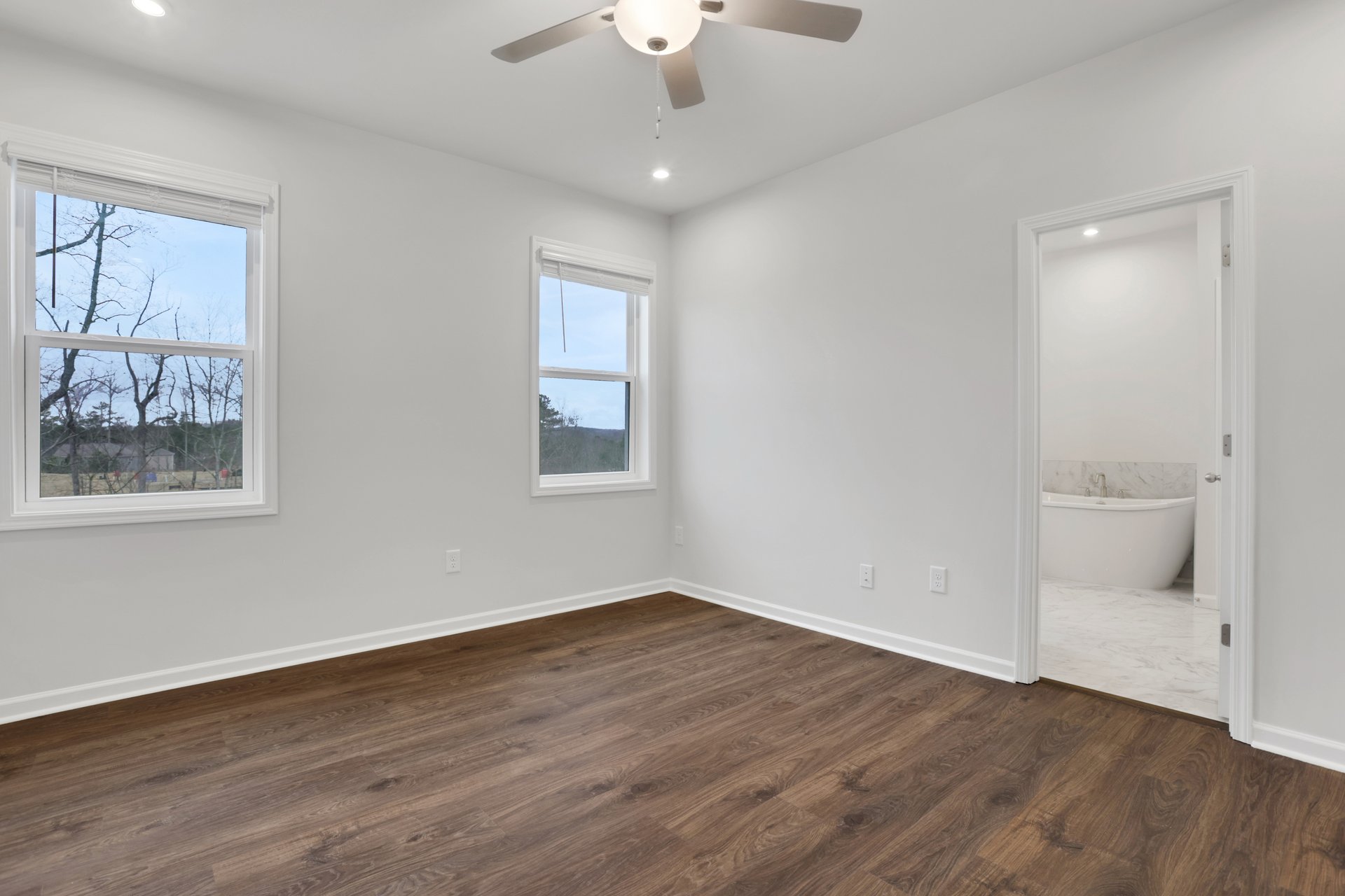 primary bedroom with windows and hard surface flooring