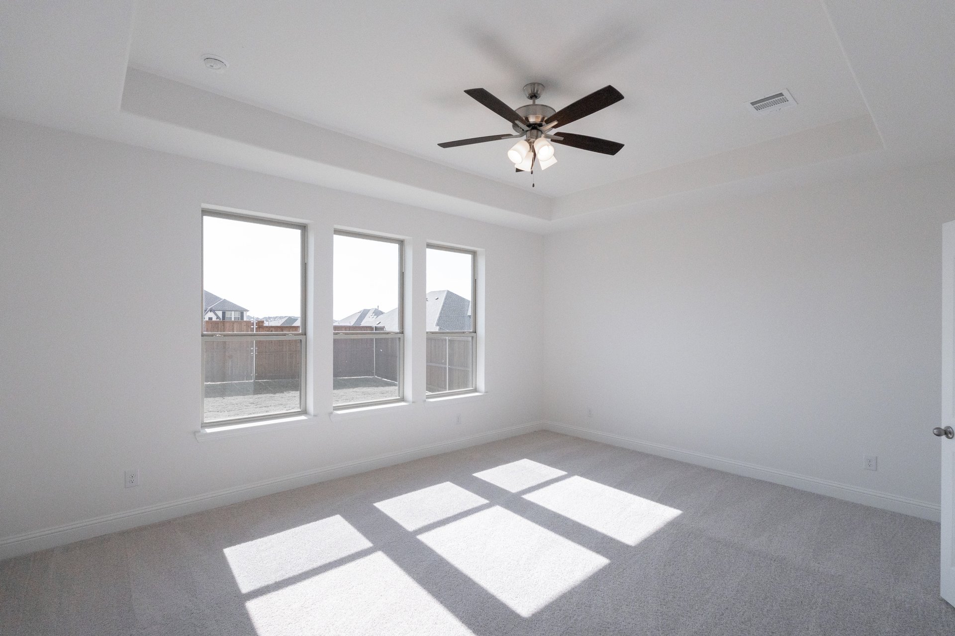 large primary bedroom with carpet and windows