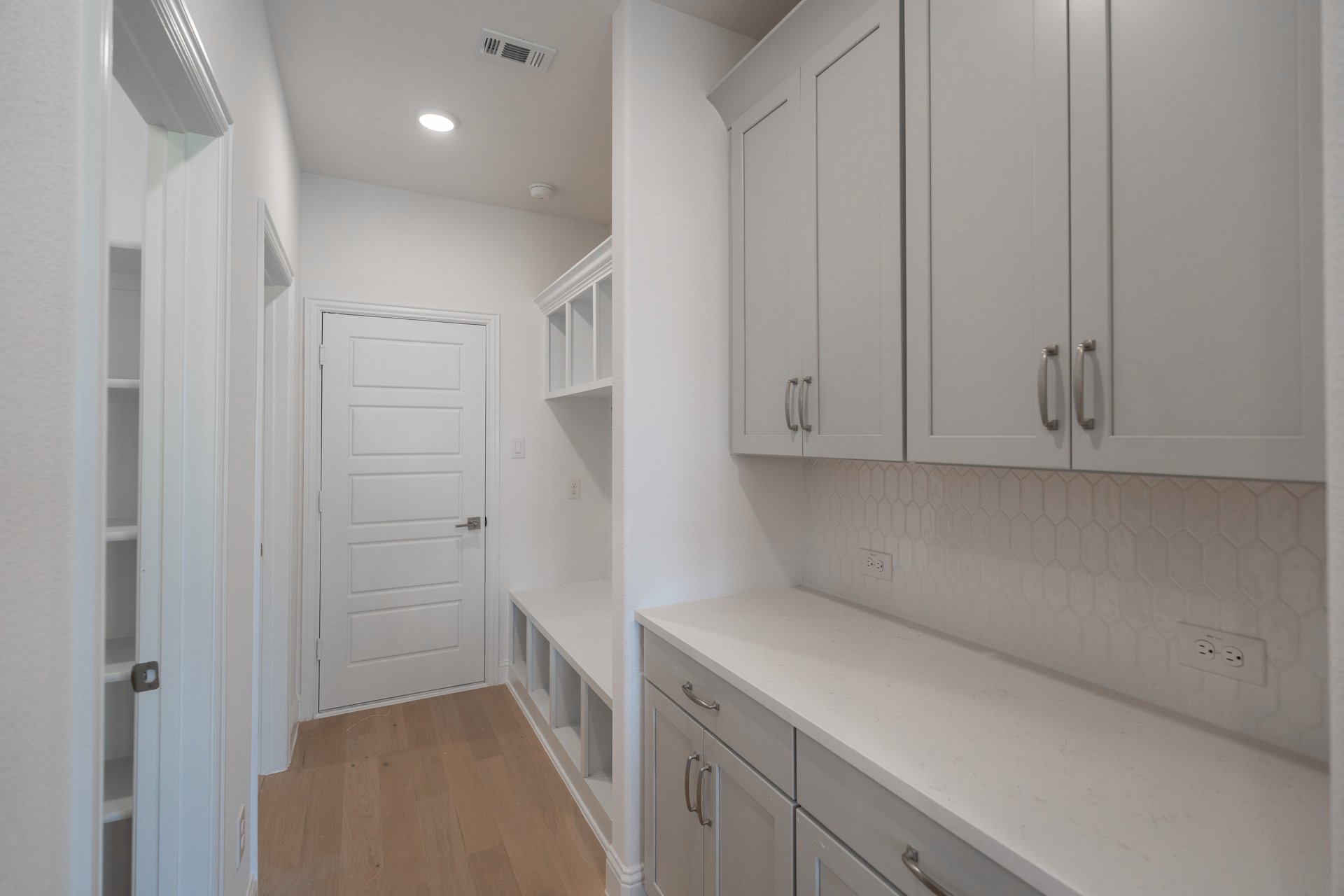 mudroom with wood flooring next to butler's pantry