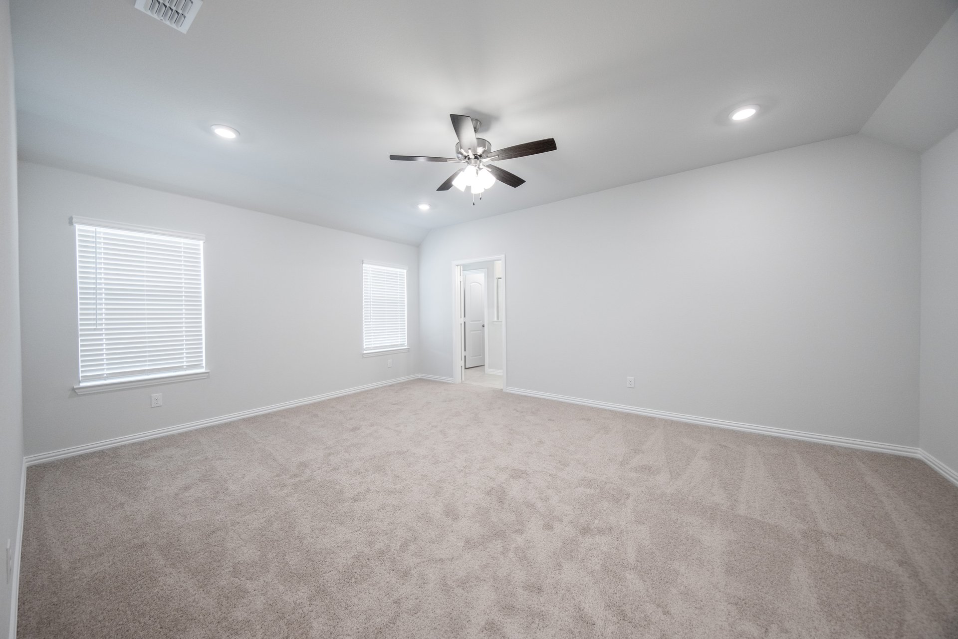 large primary bedroom with carpet and windows