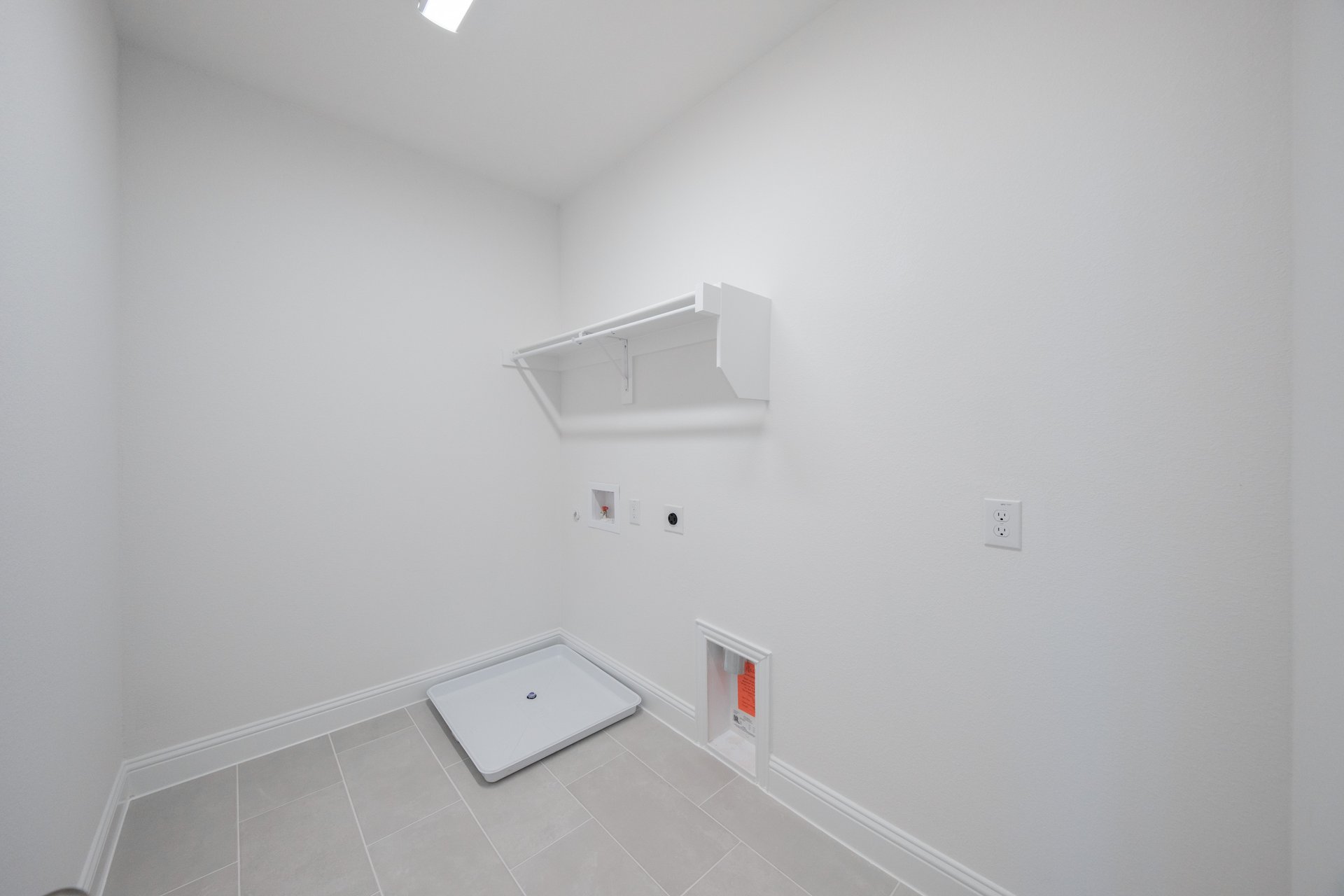 laundry room with tile floors and white shelf