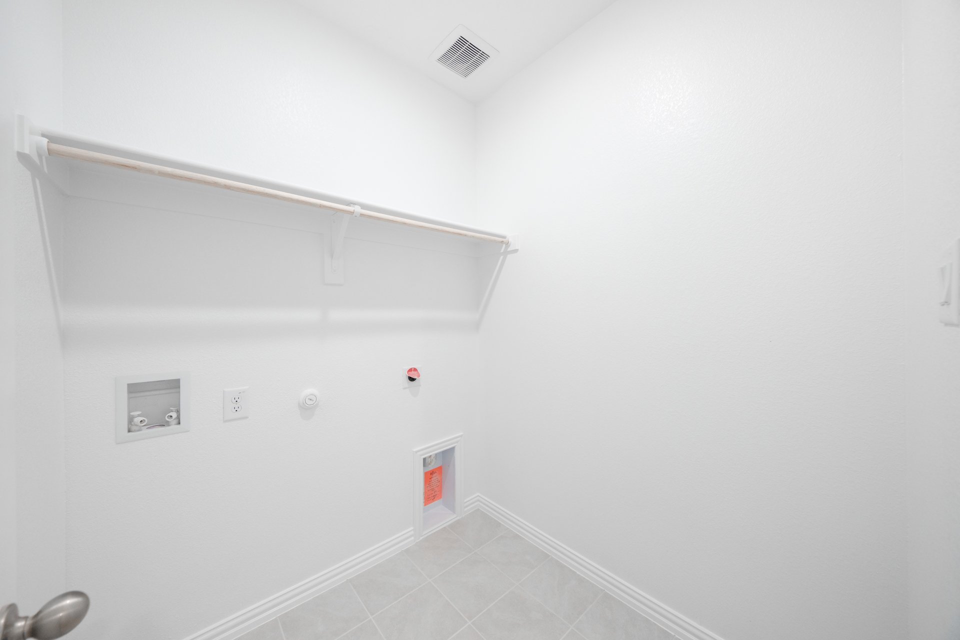 laundry room with tile floors and white shelf