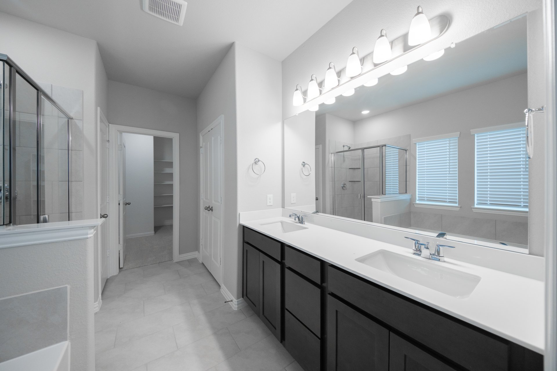 primary bathroom with dark cabinets and tile floors
