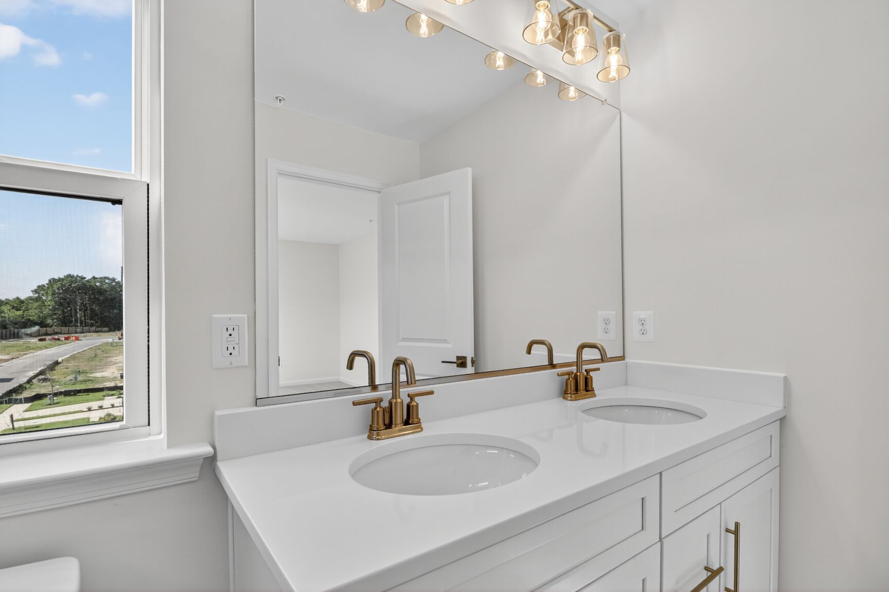 dual vanity in the primary bathroom with lighting sconces above mirror
