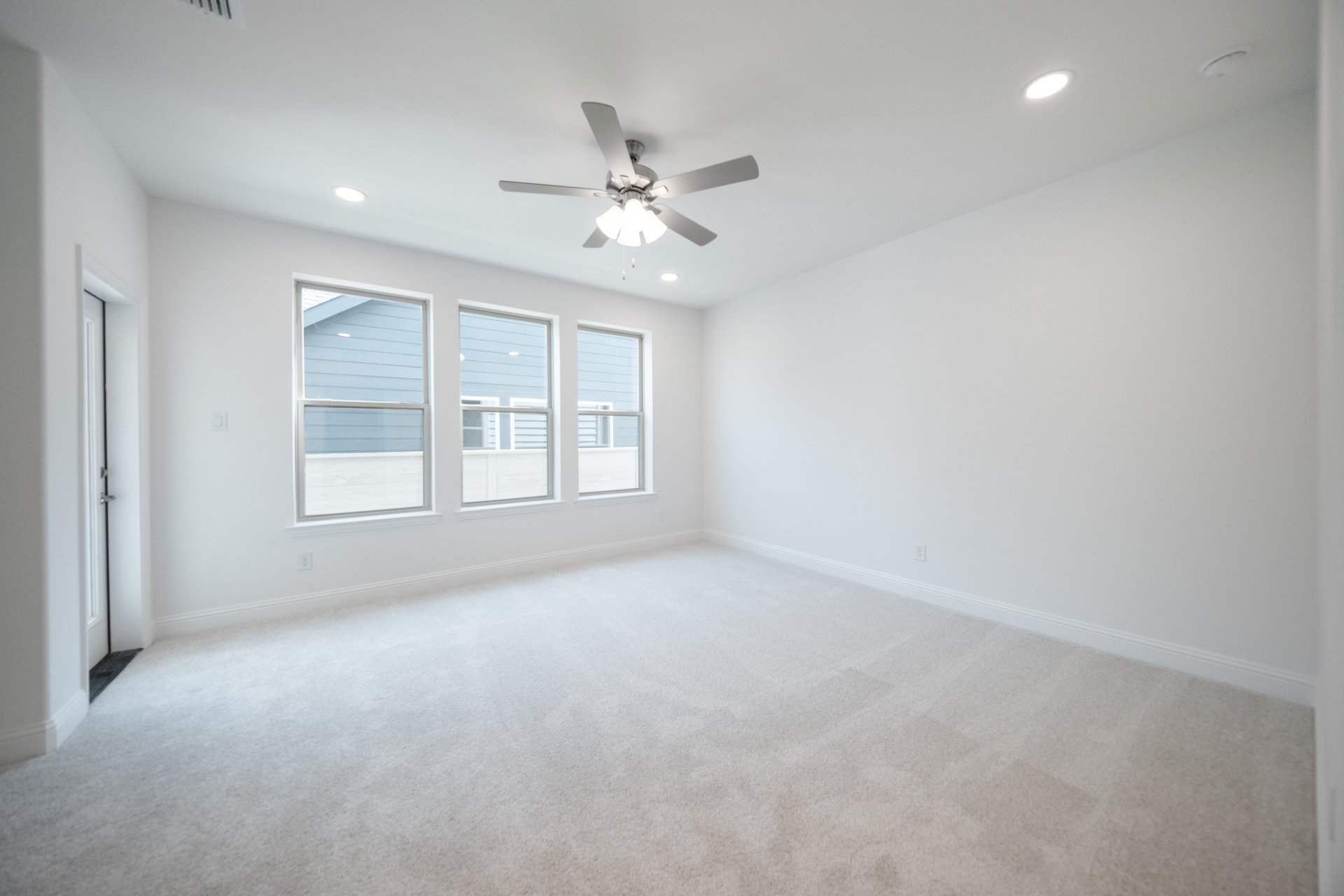 large primary bedroom with carpet and windows