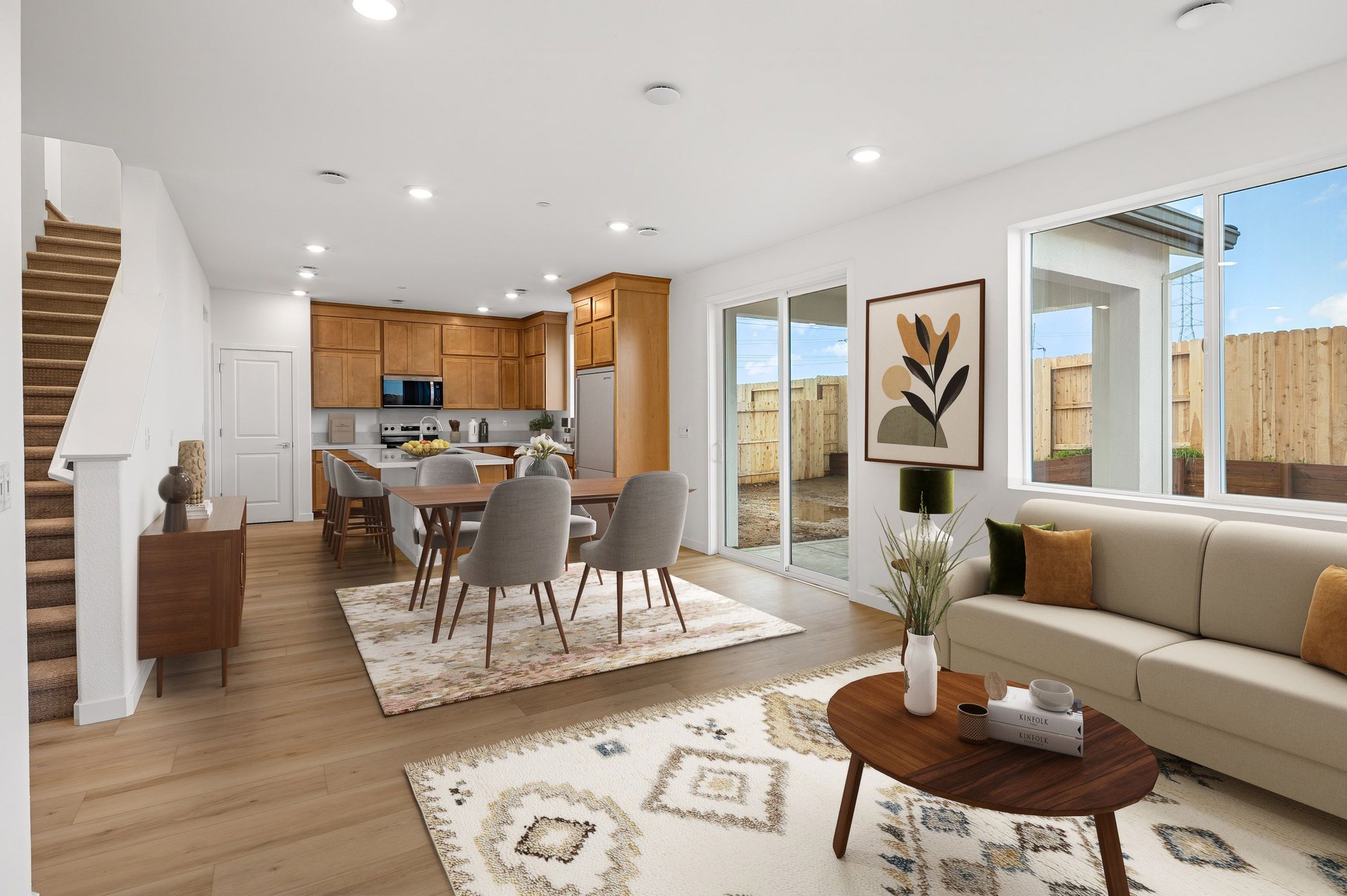 great room with wood floors, light tan sofa with black & gold pillows, and patterned neutral area rug
