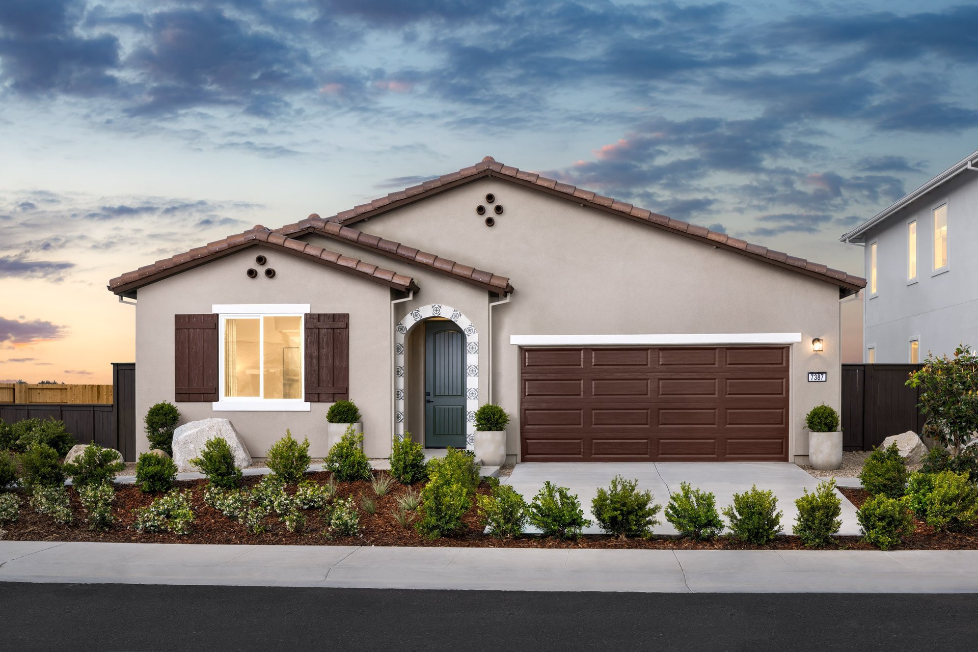 front exterior of brown single-story spanish style home at dusk