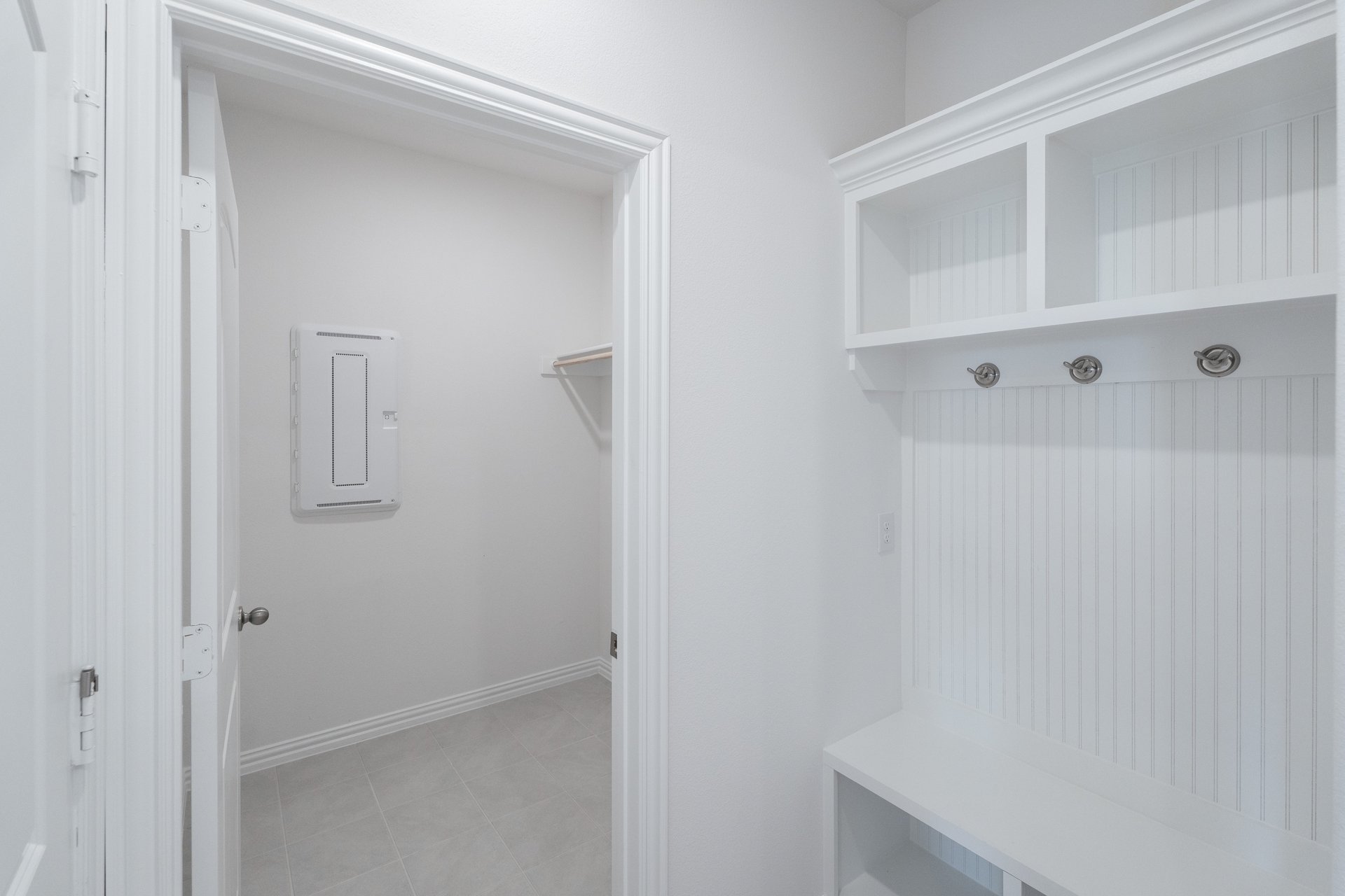 mudroom with wood floors and white shelves with bench