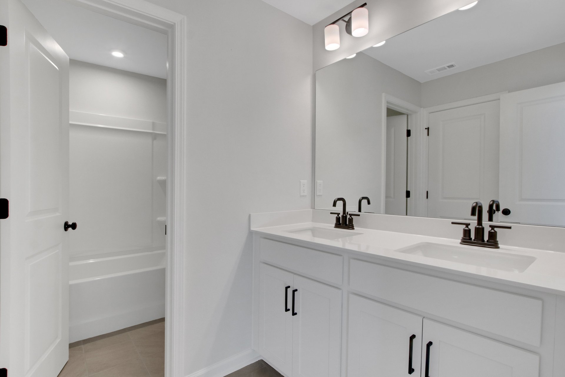 secondary bathroom with white cabinets and tile flooring