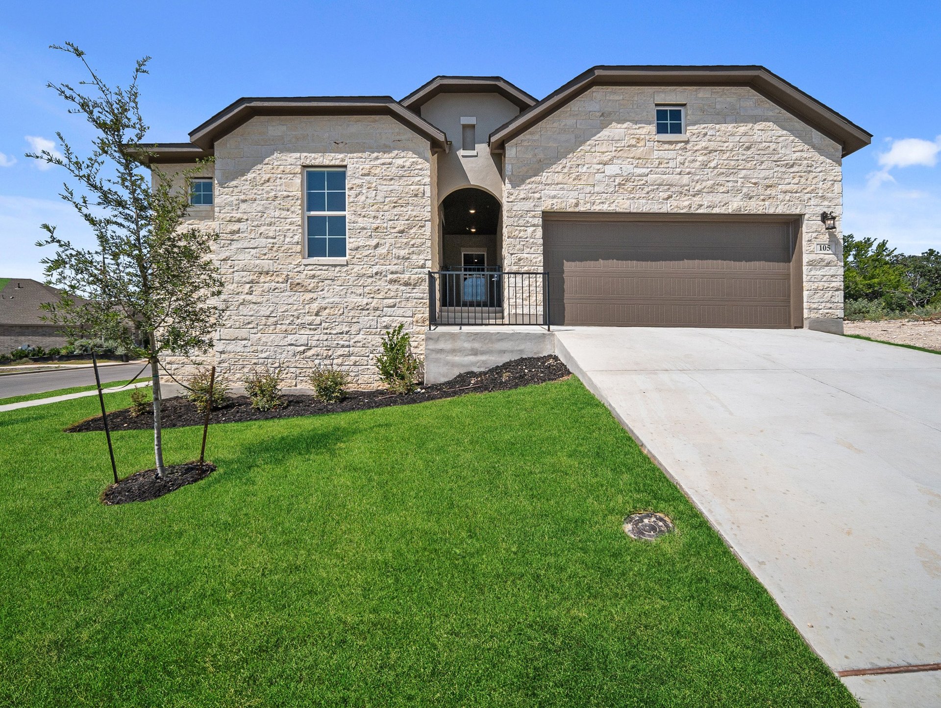 stone exterior with grass, a tree & a porch