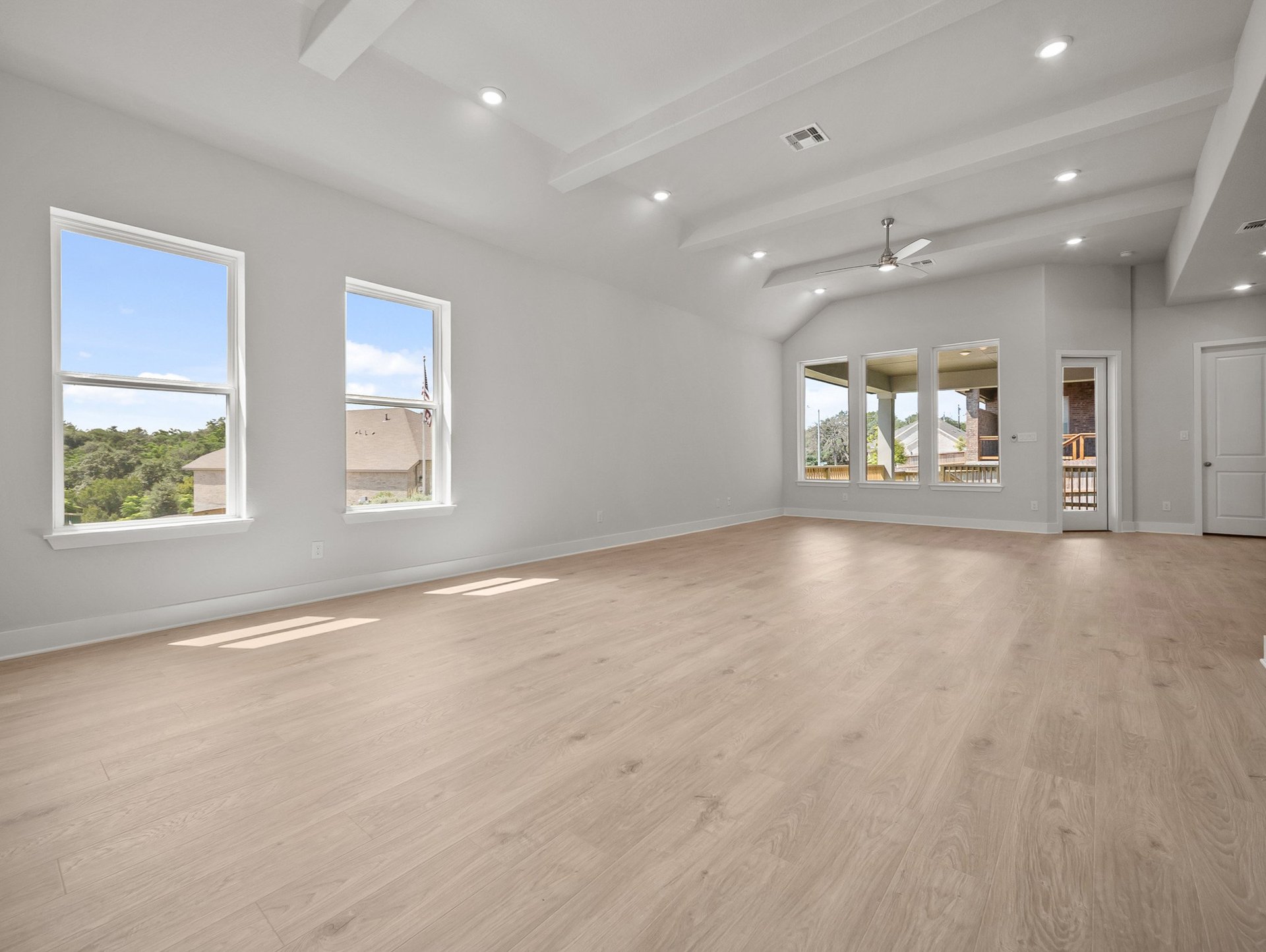 great room with brown flooring, windows & a ceiling fan