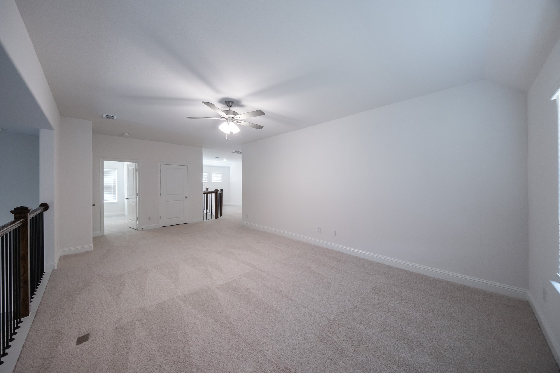 open loft with carpet and ceiling fan