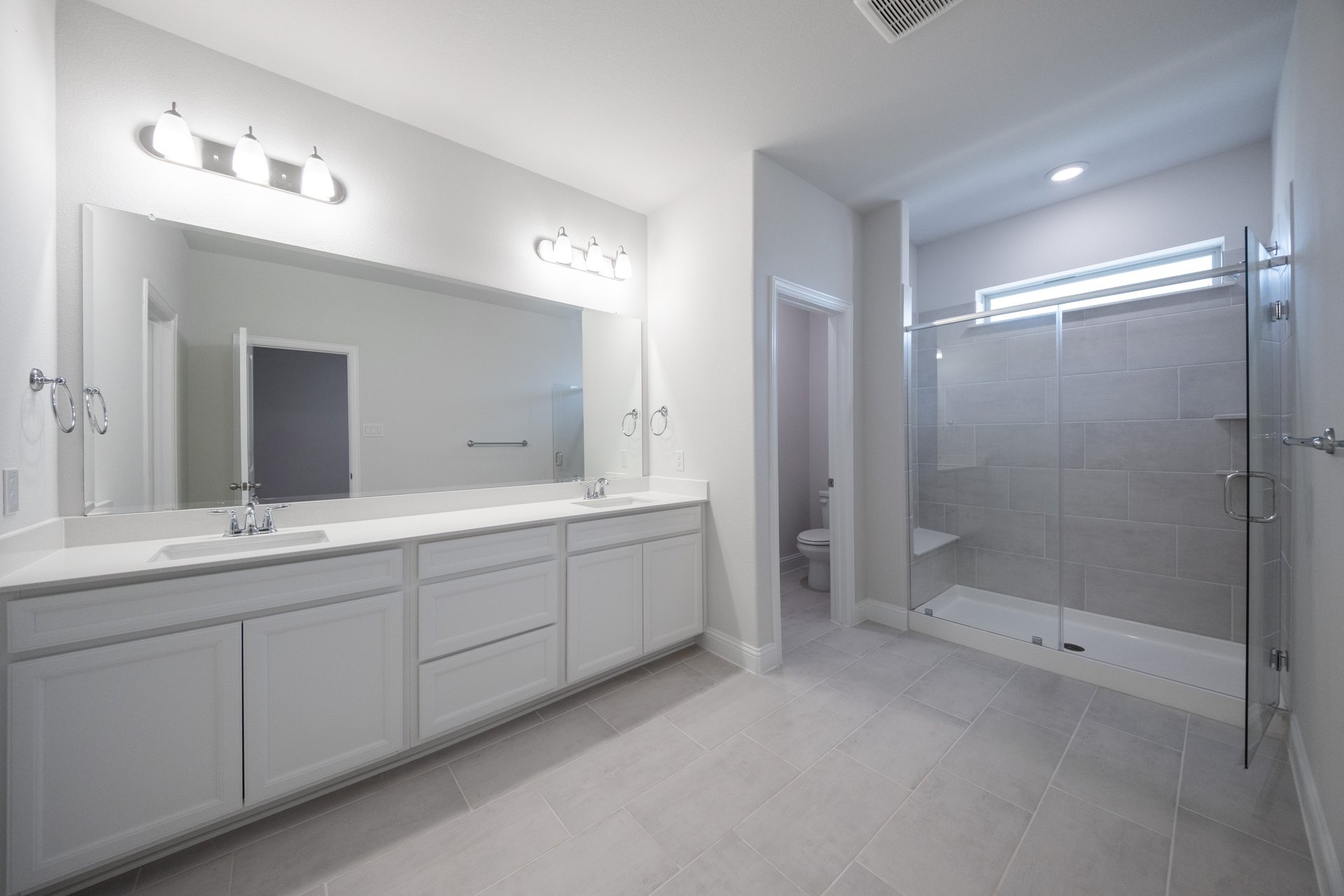 spacious primary bathroom with double sinks and walk-in shower