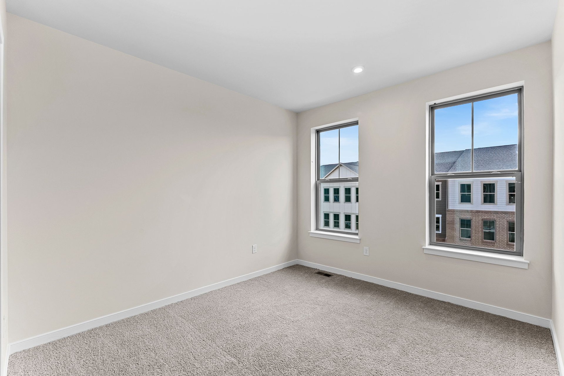 secondary bedroom with two windows and carpet