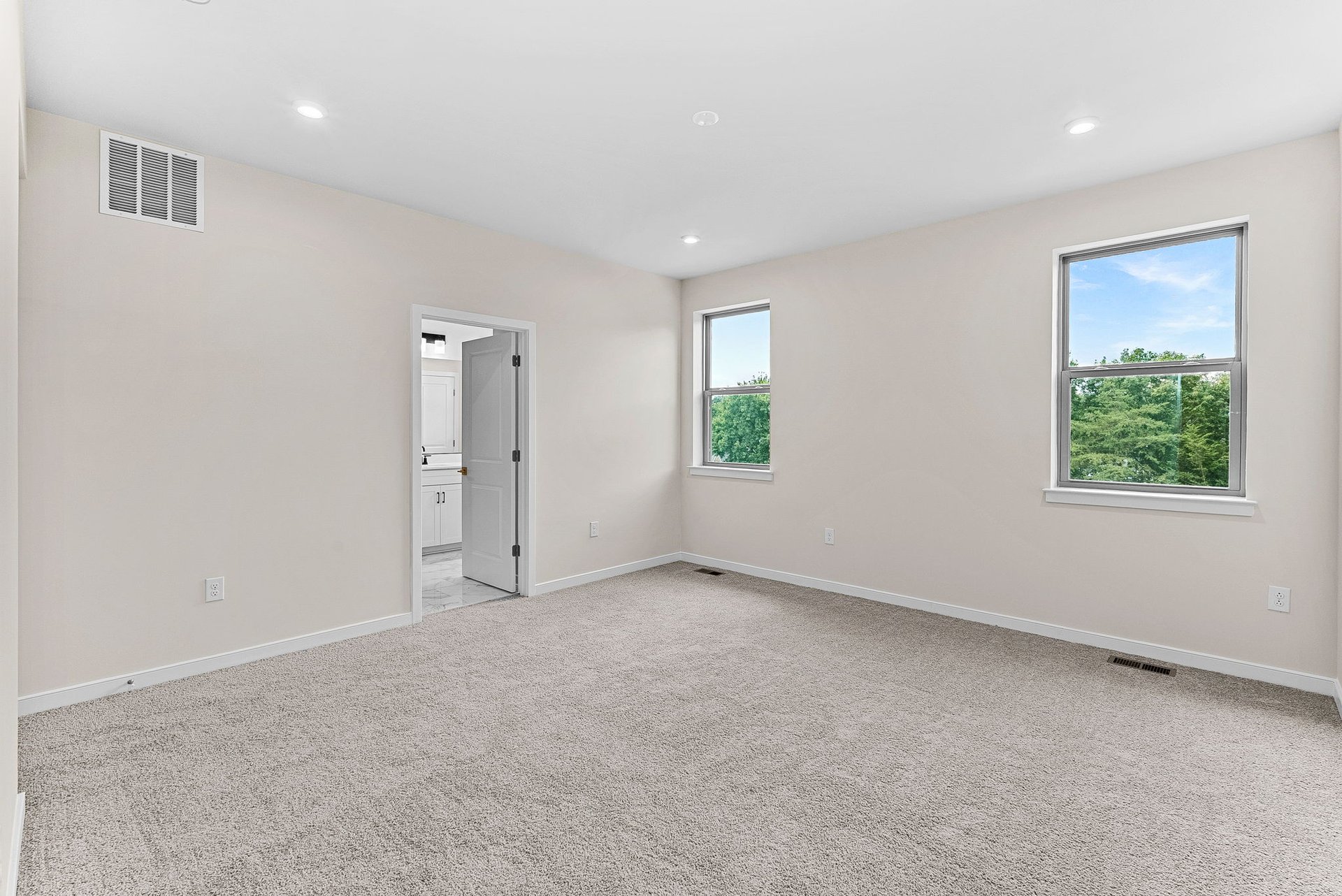 primary bedroom with two windows and carpet