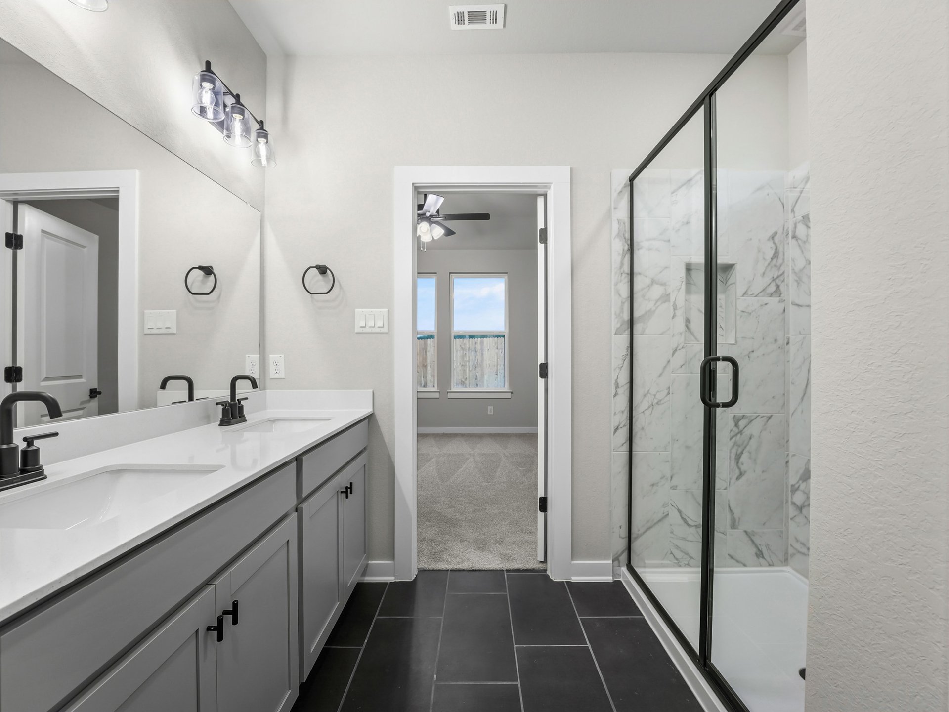 primary bathroom with black flooring, dual sinks and walk in shower