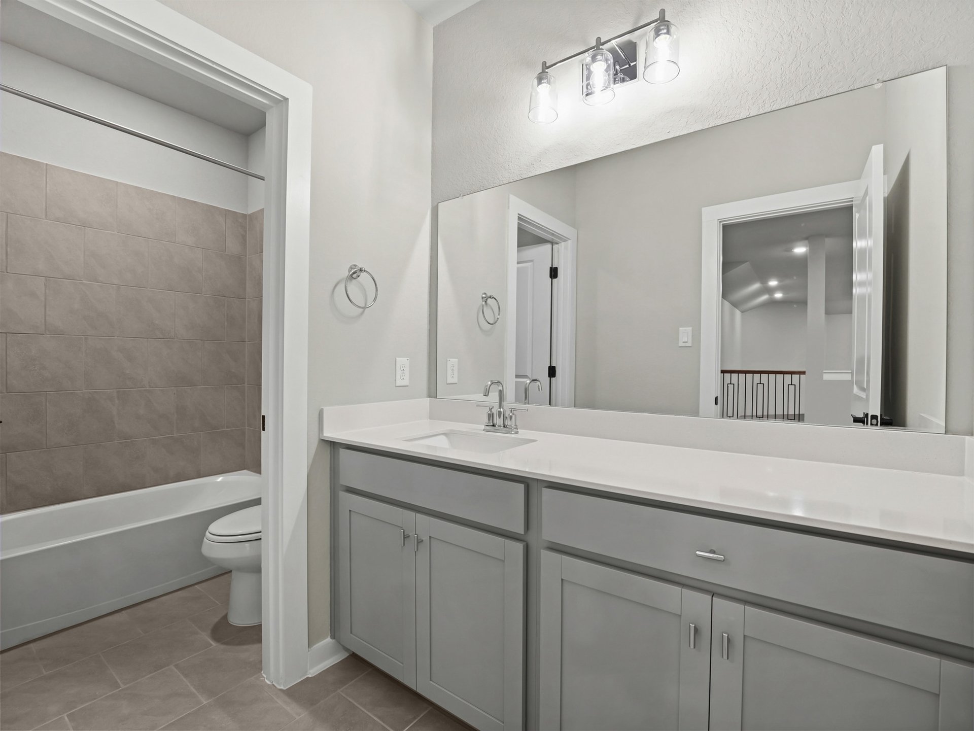 secondary bathroom with grey cabinets, white countertops and soaking tub