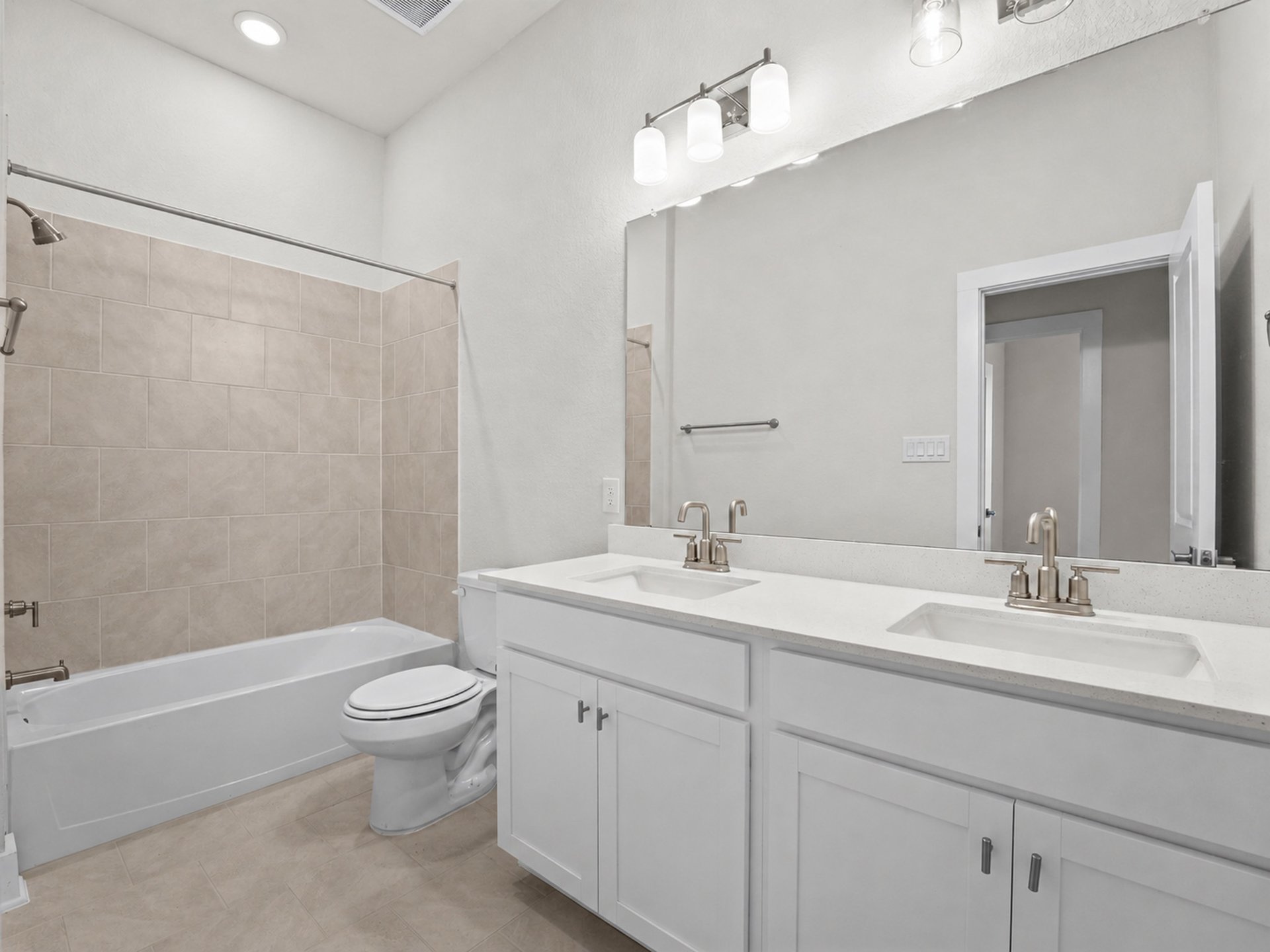 secondary bathroom with soaking tub, dual sinks and beige flooring 