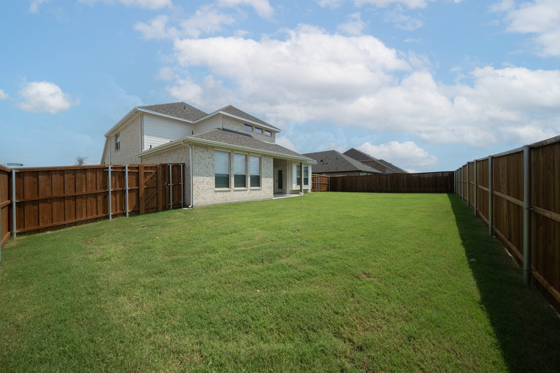 large fenced backyard with grass 