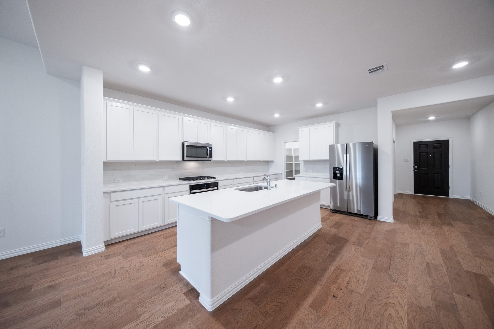 open kitchen with wood floors and white cabinets