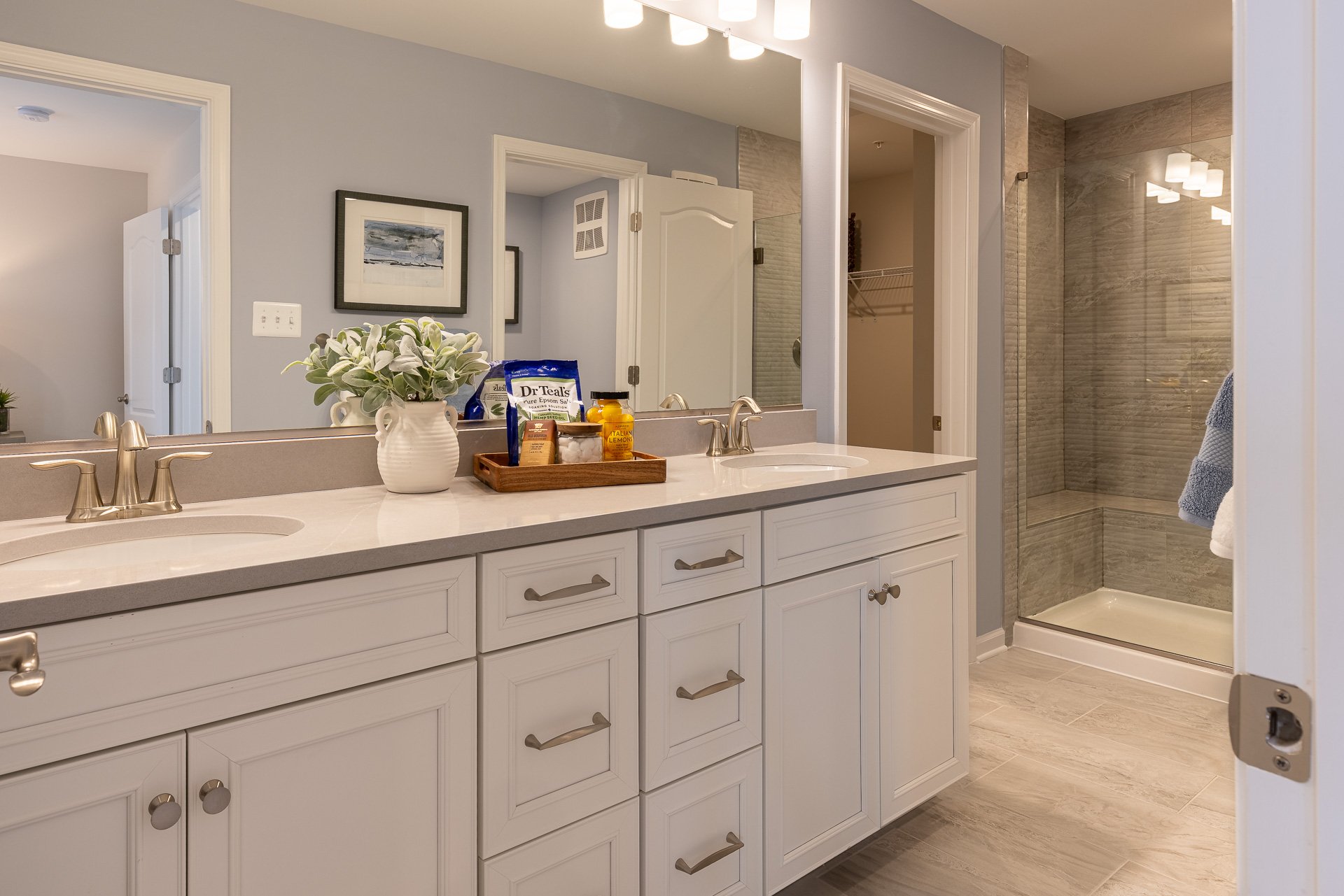 primary bath with dual vanities and an oversized shower