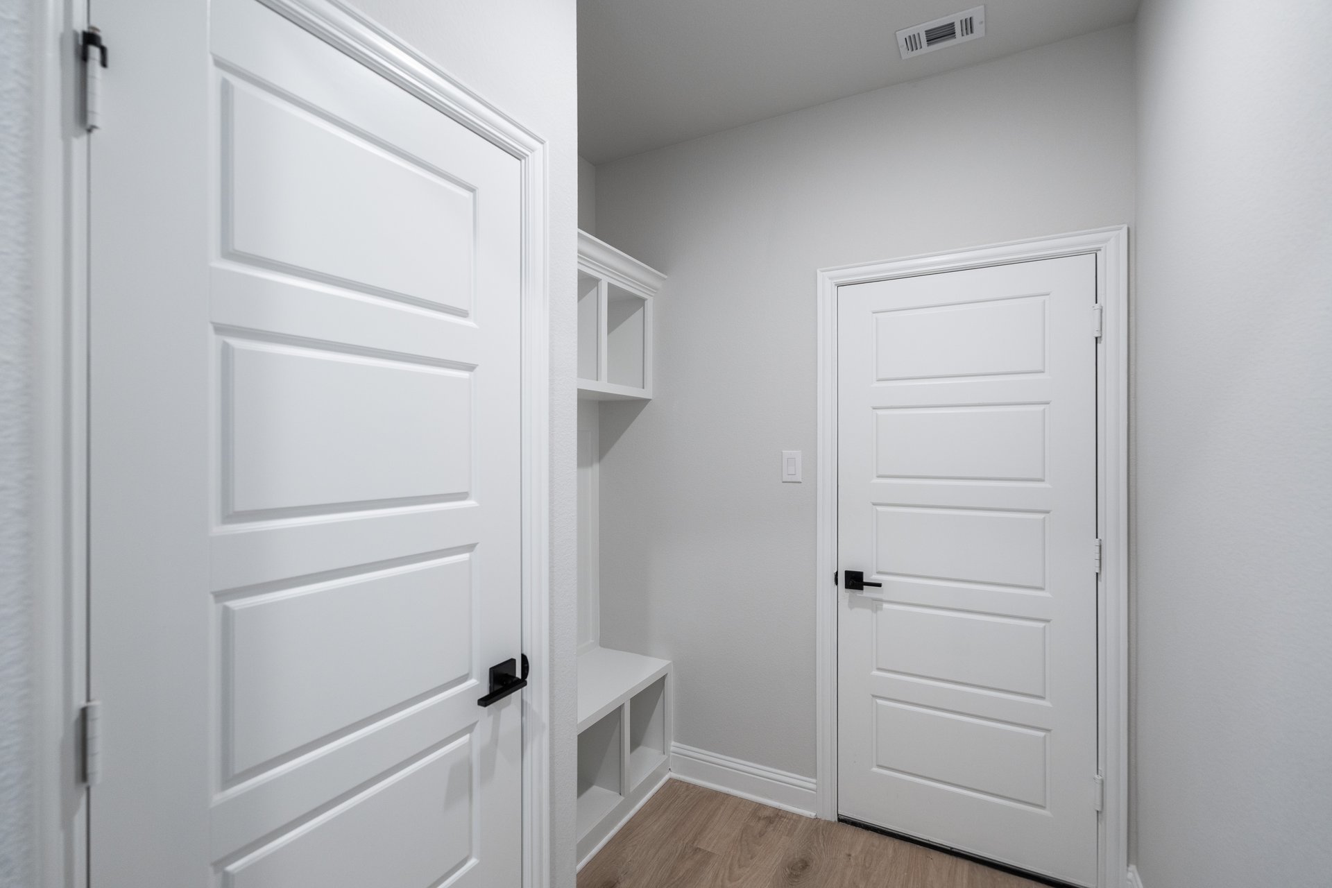 mudroom with wood floors and white shelves with bench