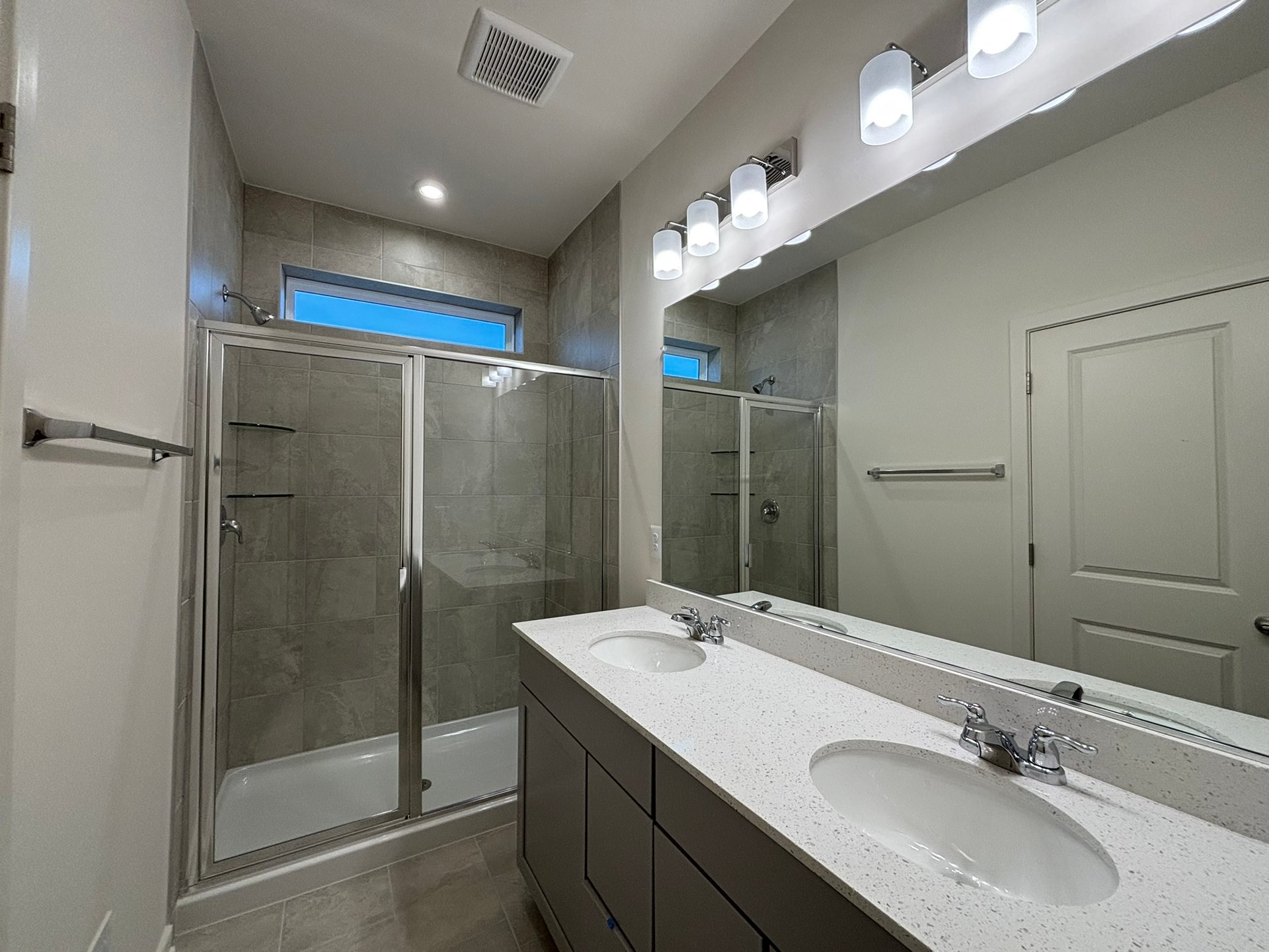 primary bathroom with two sinks and an oversized shower