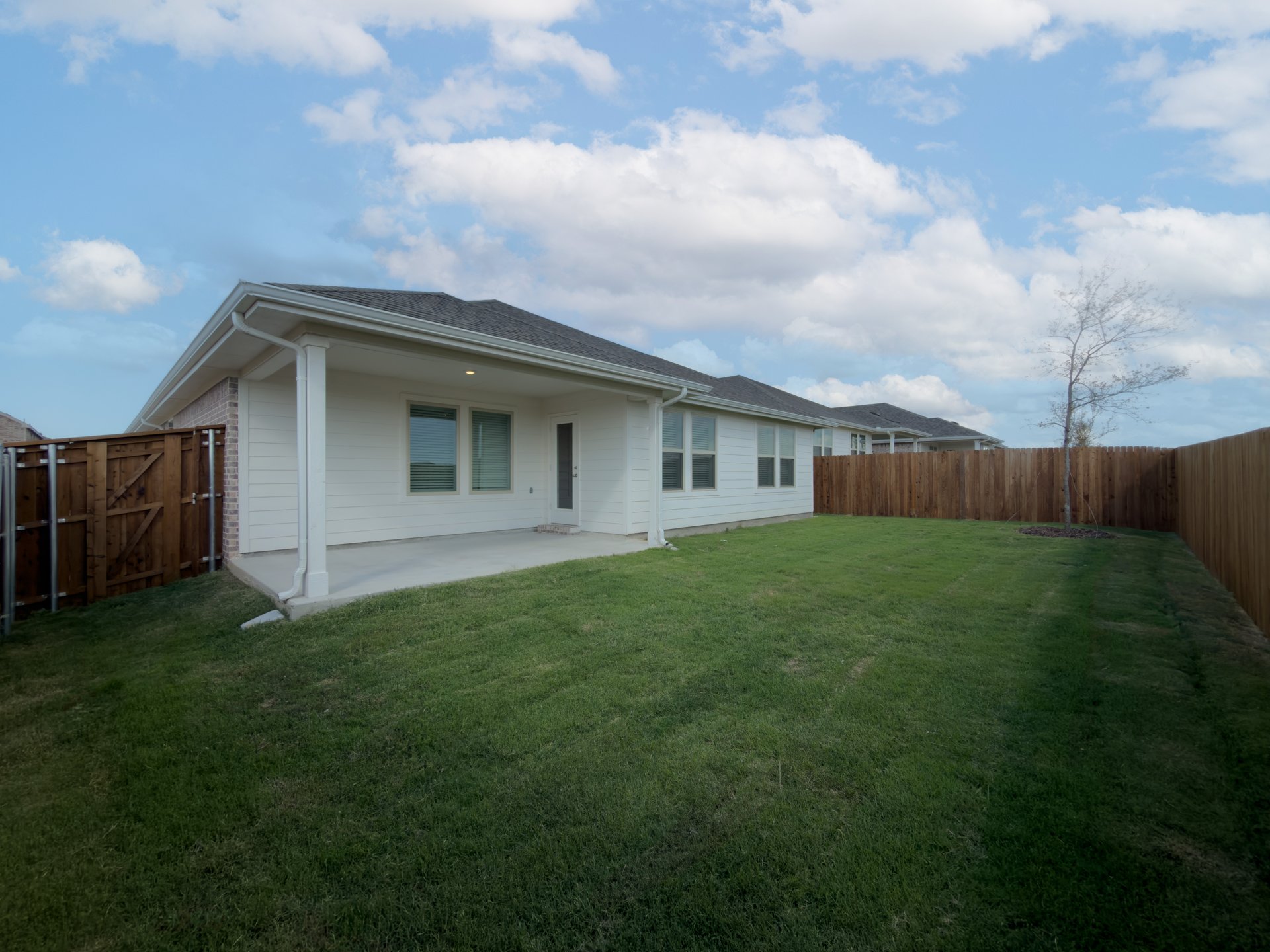 covered patio that opens up to fenced backyard