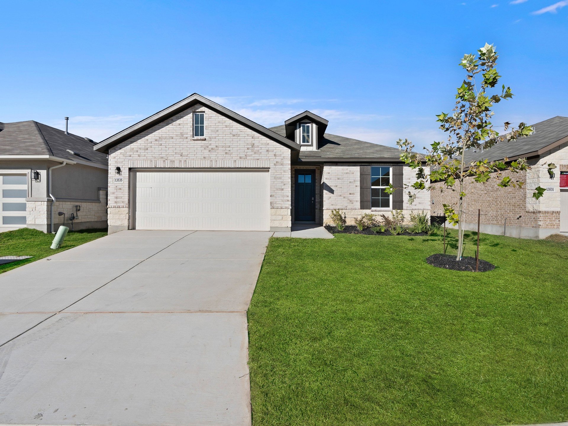 brick exterior with tree, garden & garage