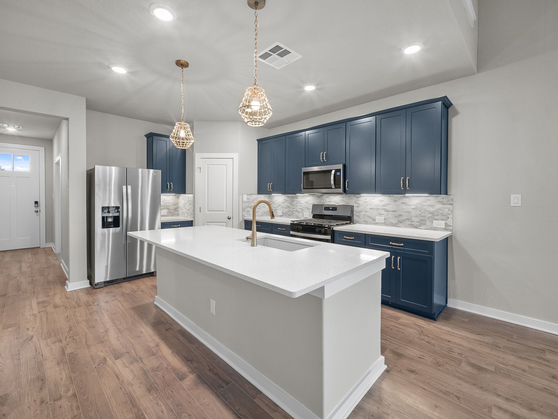 kitchen with blue cabinets, pendant lighting & quartz countertops