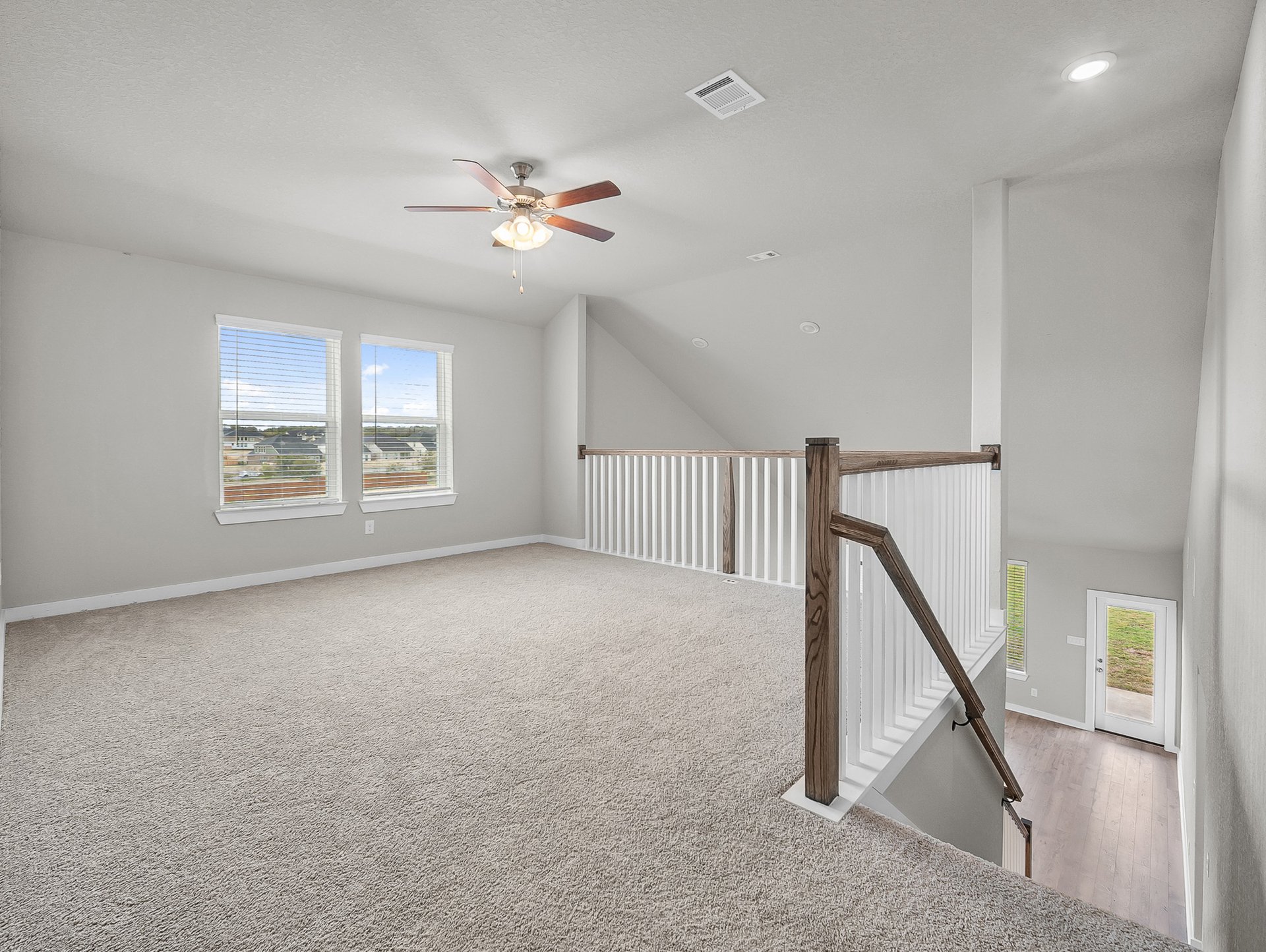 loft with carpet, ceiling fan & a window