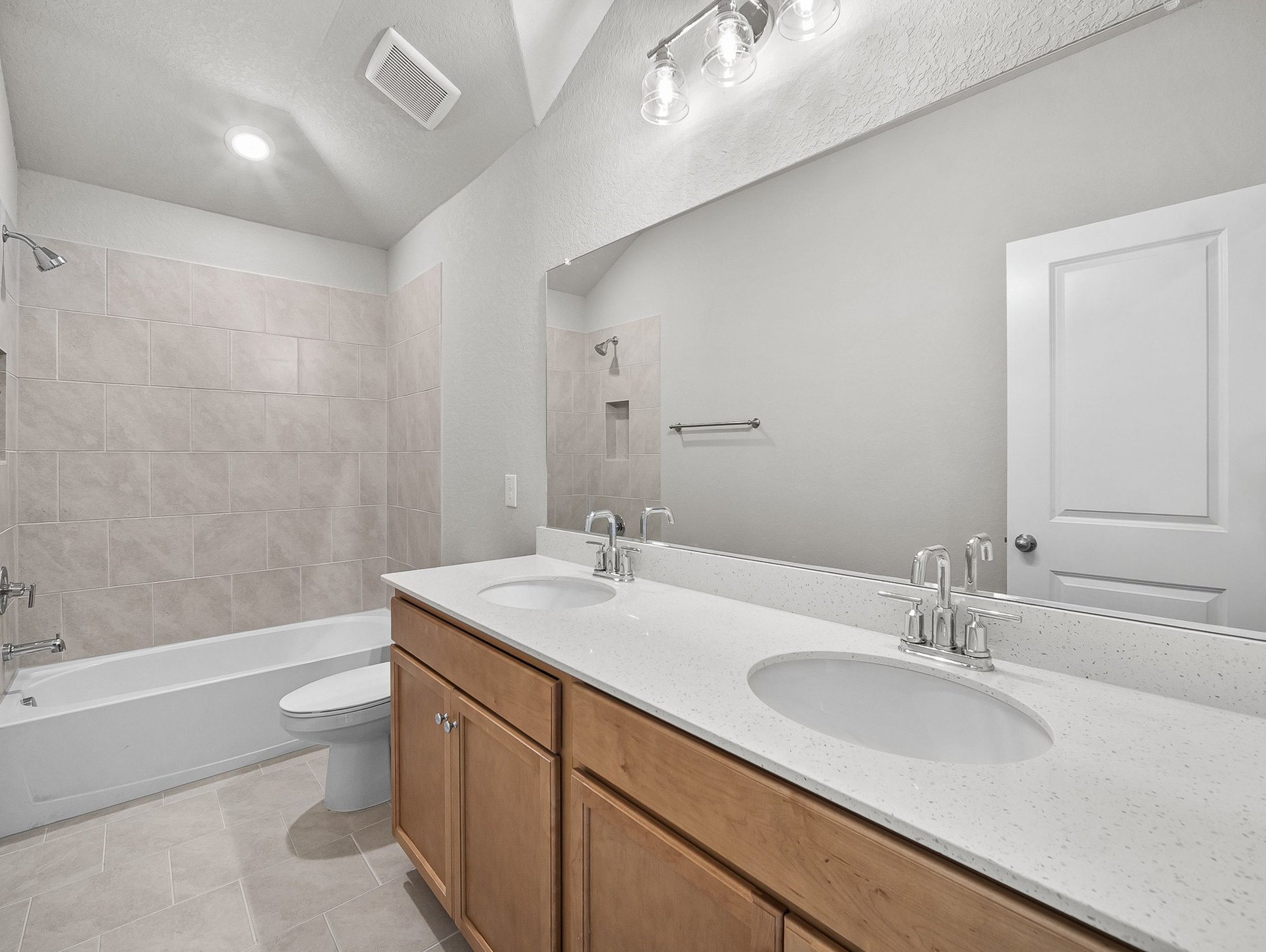 bathroom with dual sinks, quartz countertops & a bathtub
