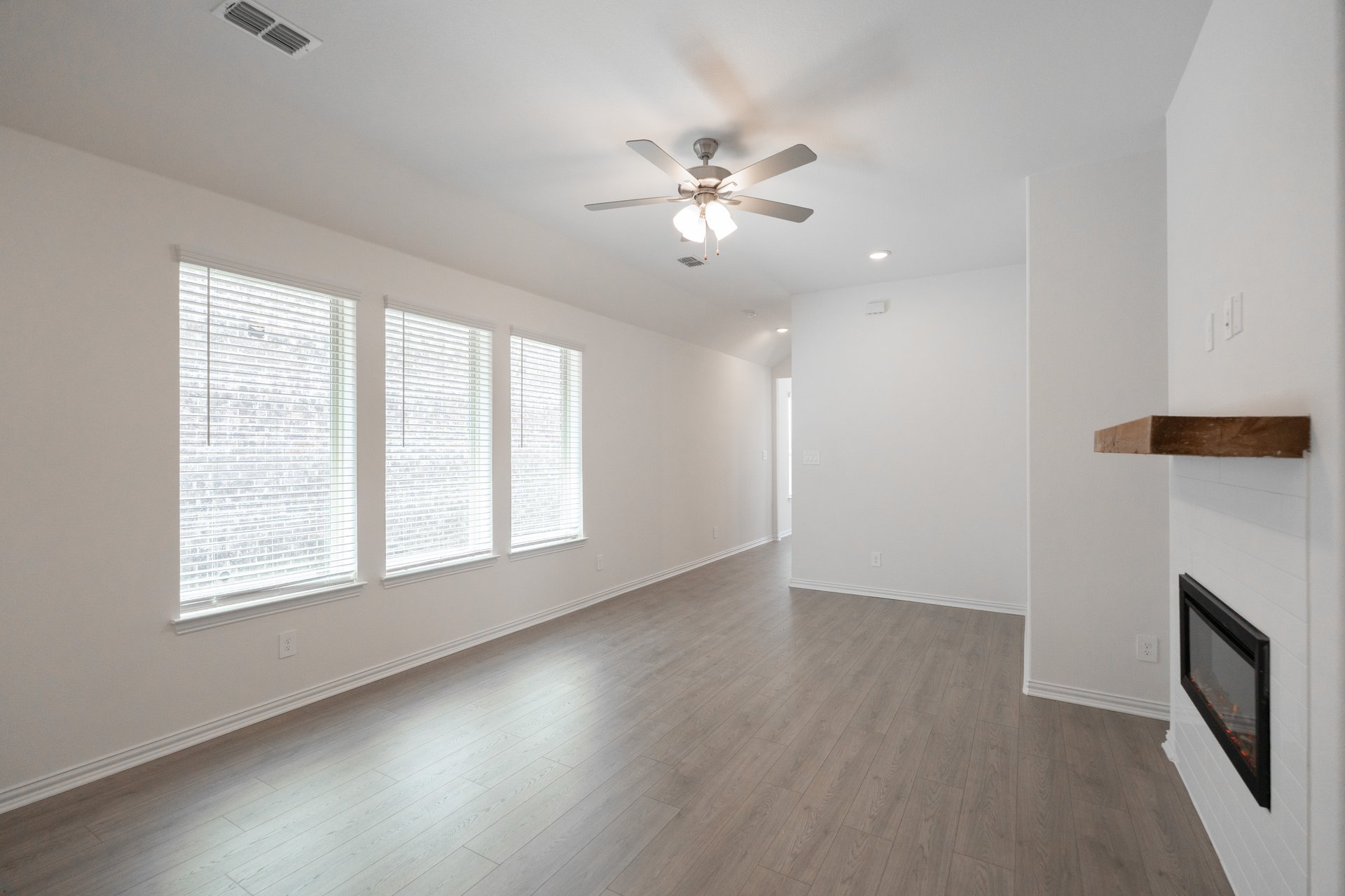 great room with windows with blinds and ceiling fan 