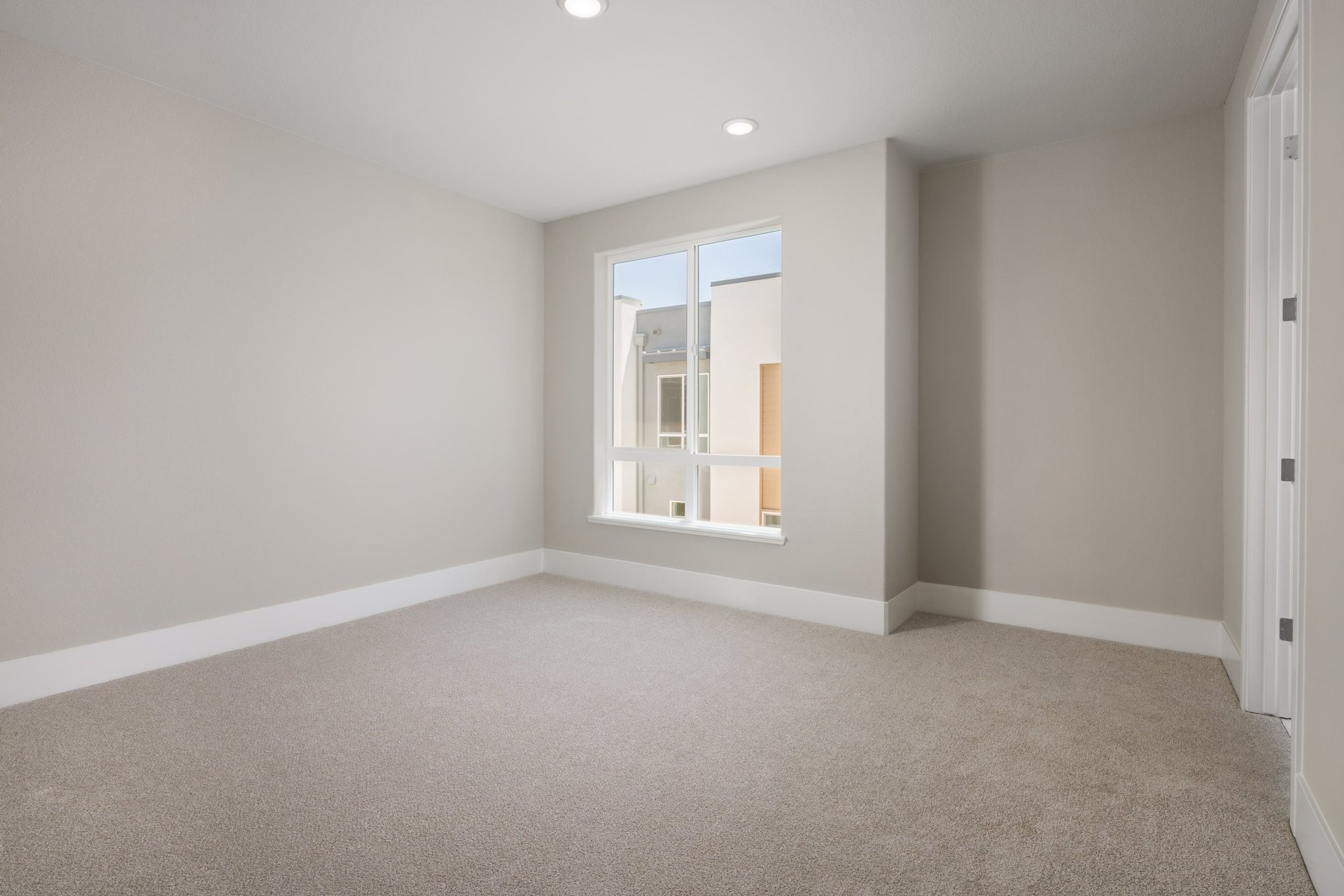 bedroom with tan carpet & walls, recessed ceiling lights, and window