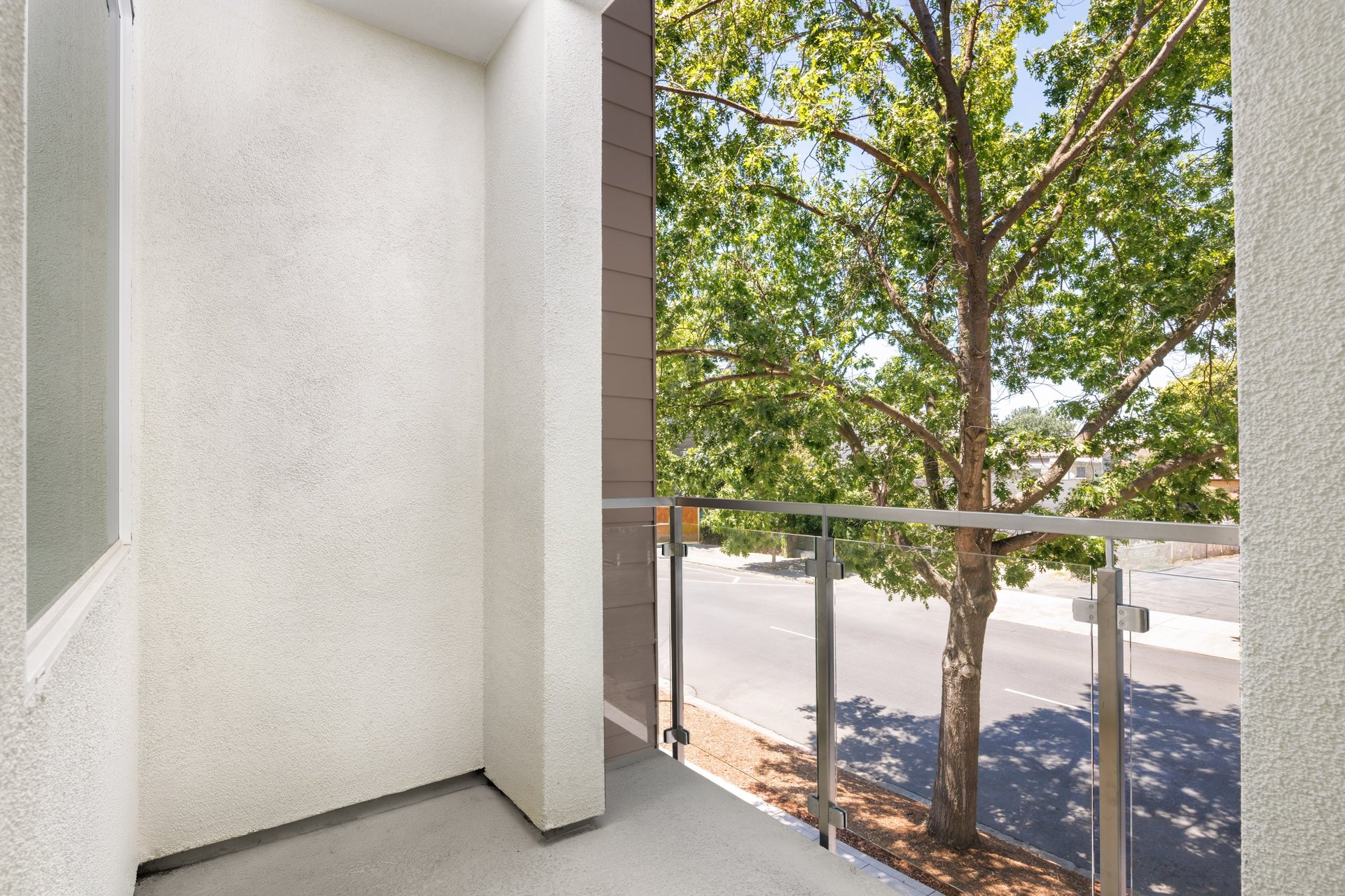 outdoor covered deck with glass enclosure and view of street with trees