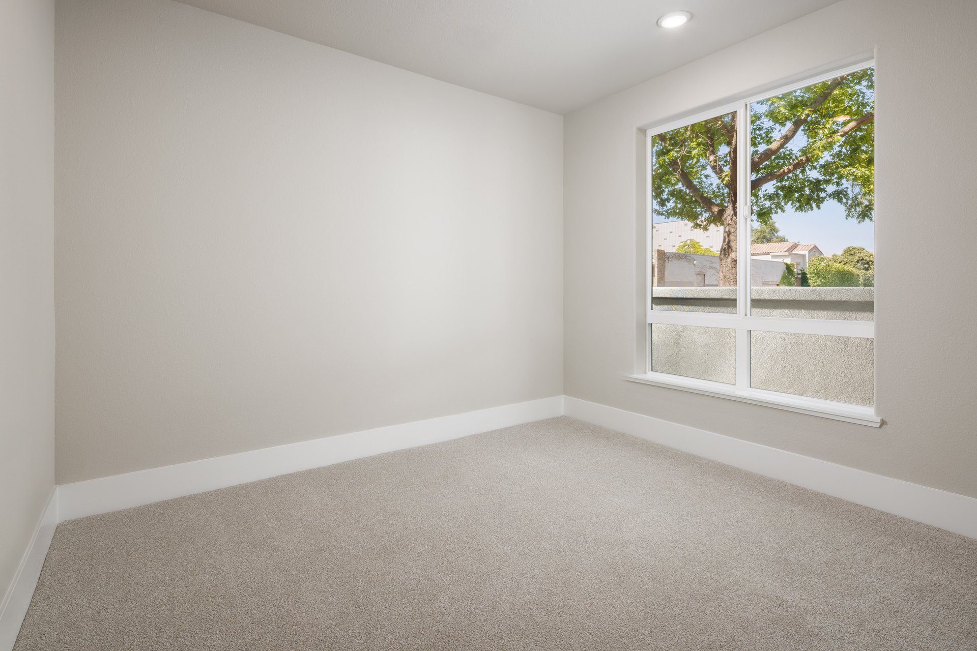 bedroom with tan carpet, tan walls, window, and recessed ceiling lights